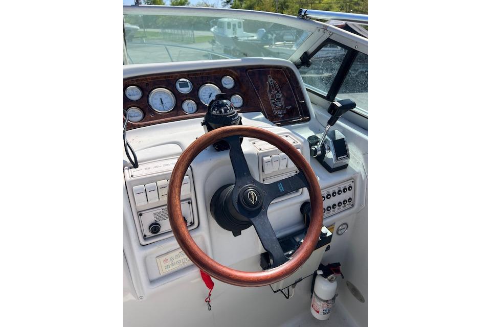 Cockpit of a 1997 Crownline 250 CR boat with wooden steering wheel and control panel.
