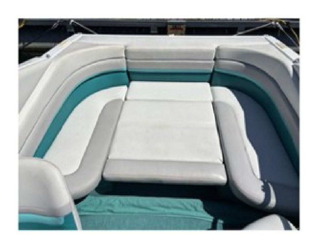 The image shows a boat seating area with white and turquoise cushions.
