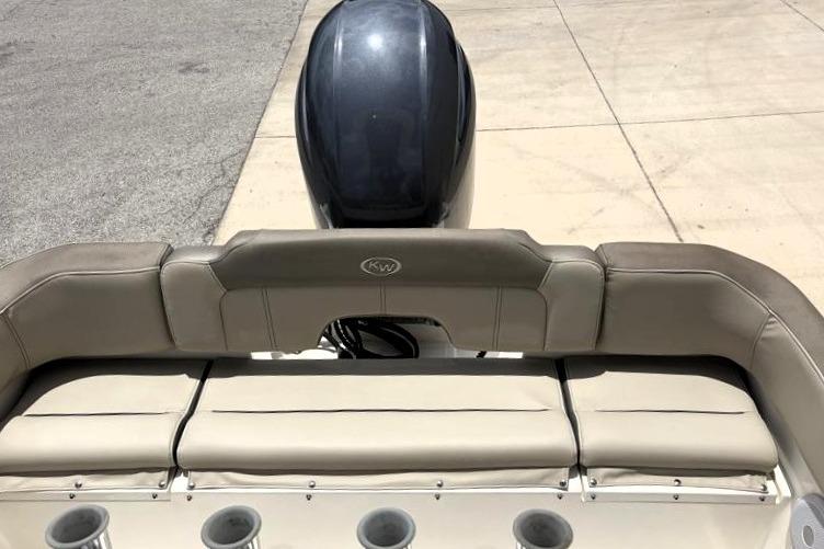 2023 Key West 203 FS boat with cushioned seating and outboard motor, docked on concrete.