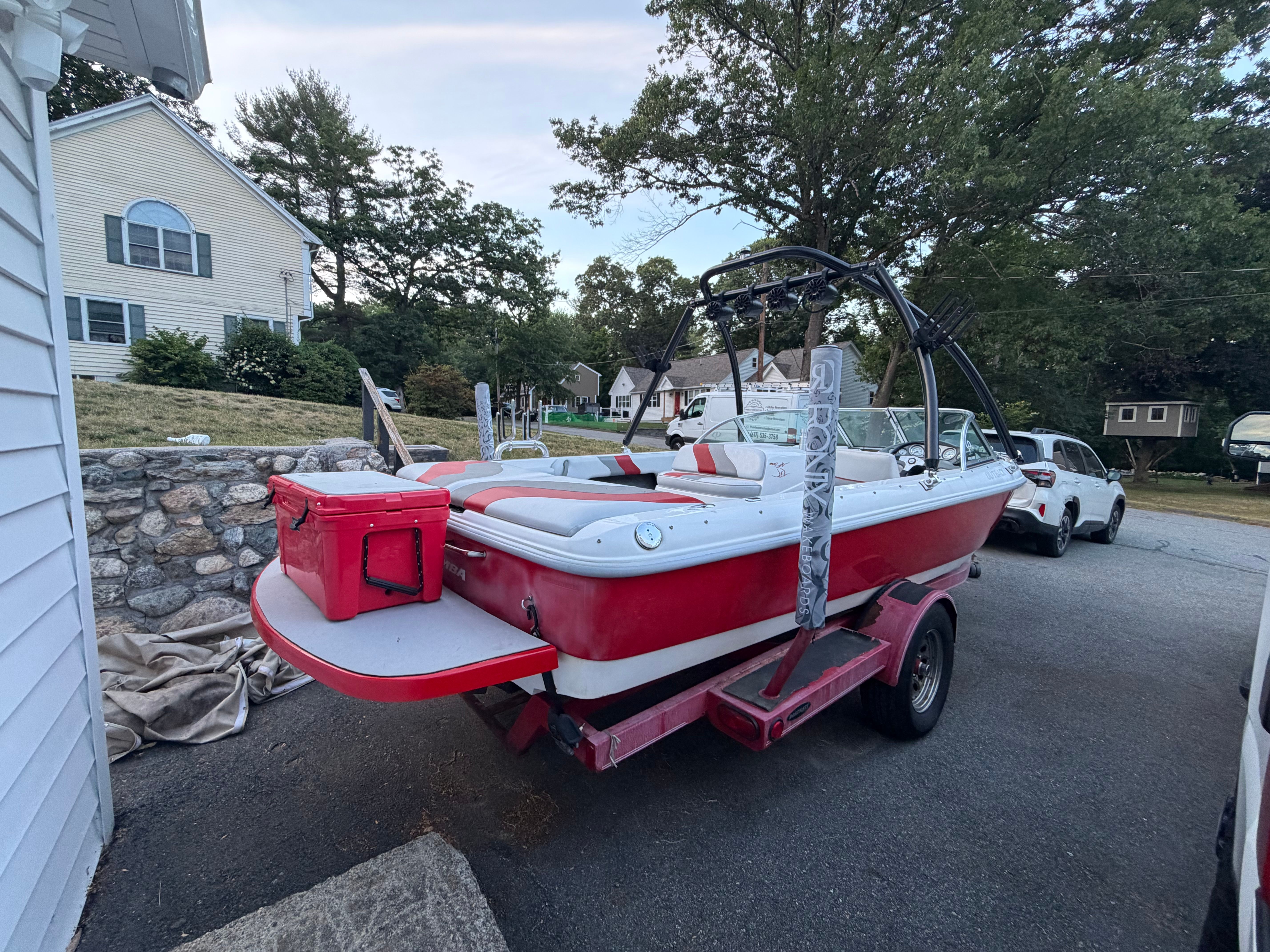 A red 2002 Moomba Outback boat is on a trailer in a driveway.