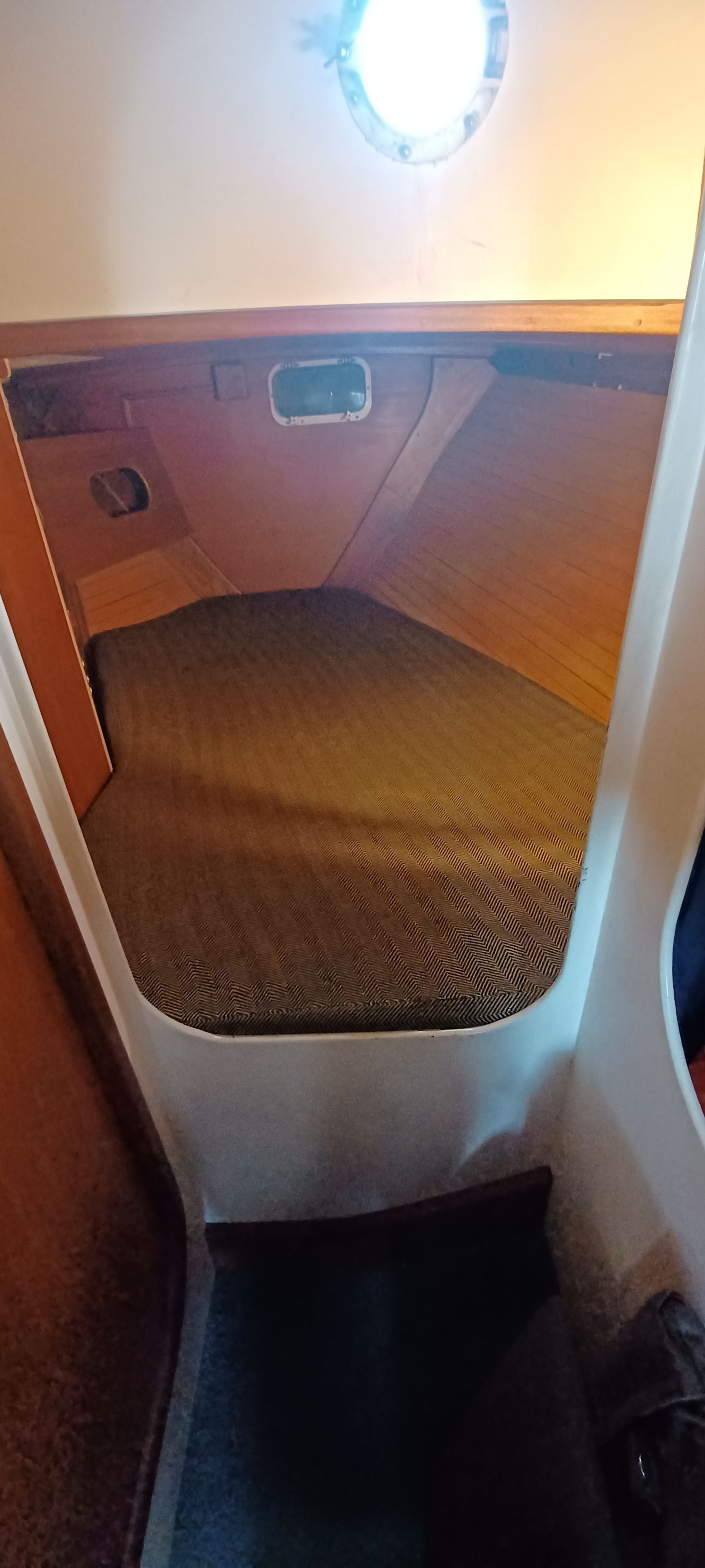 Interior of a sailboat with a cozy sleeping cabin and porthole.