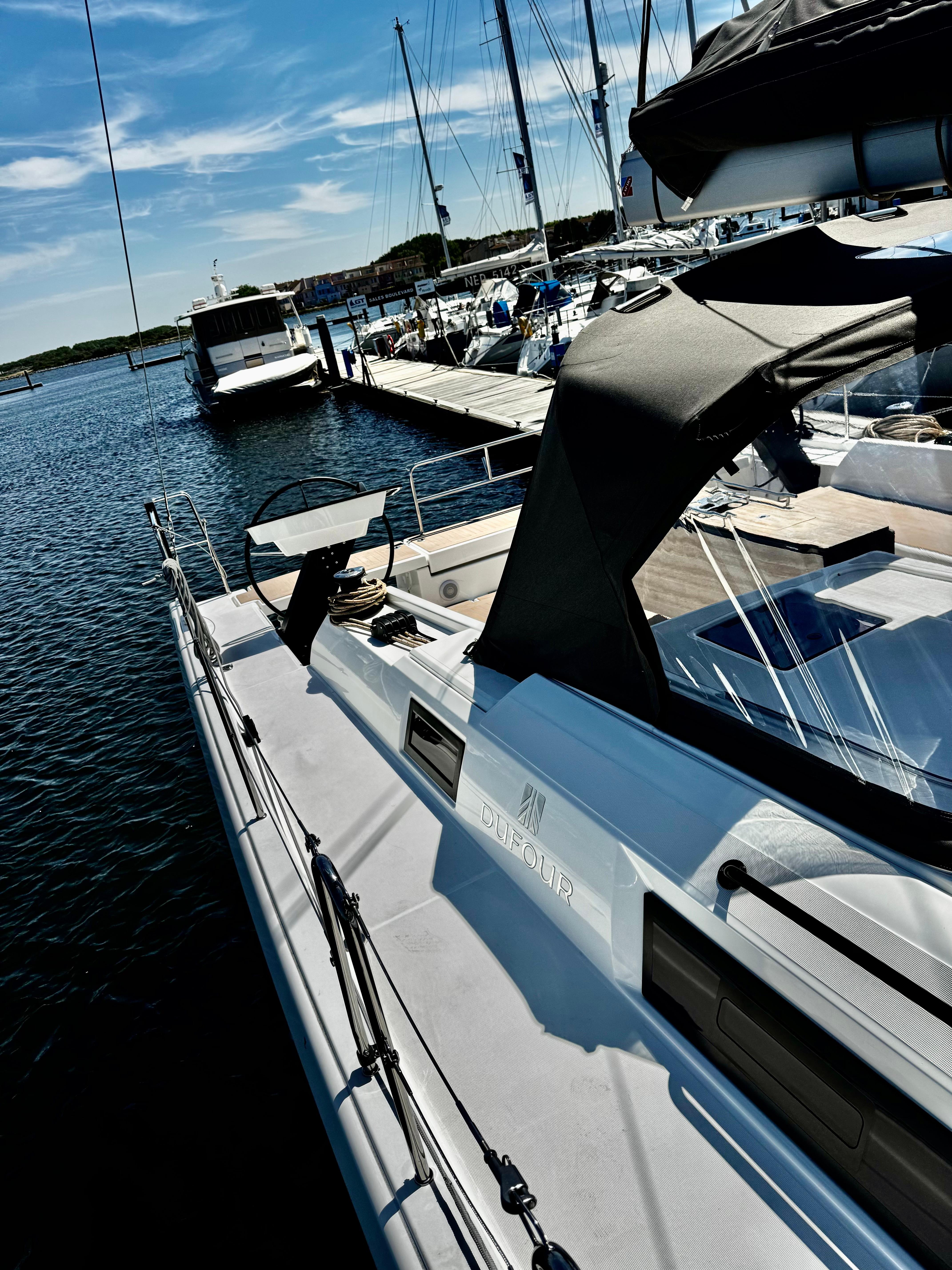 2024 Dufour 470 yacht docked at marina under clear blue sky.