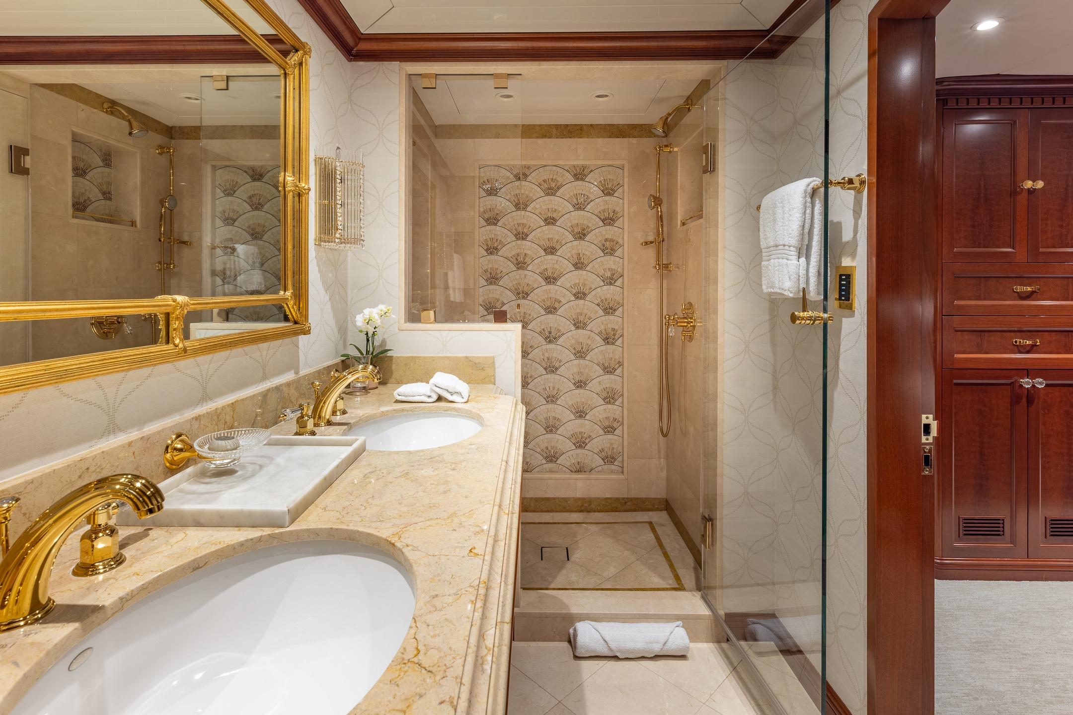 Luxurious bathroom on 2001 TRINITY Tri-Deck MY yacht with marble countertops and gold fixtures.