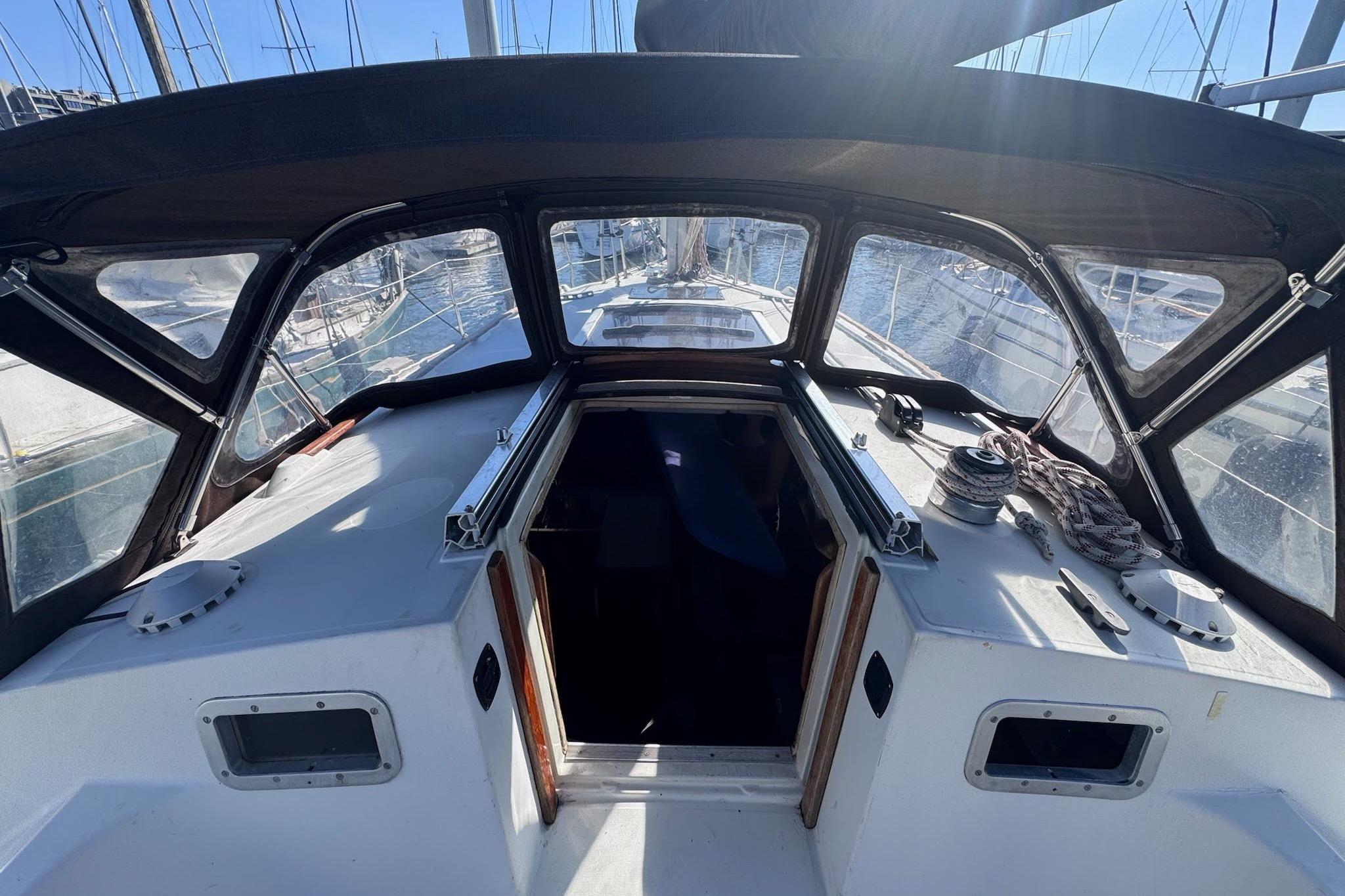 Cockpit view of a 1985 Beneteau First 375 sailboat with open hatch and winches.