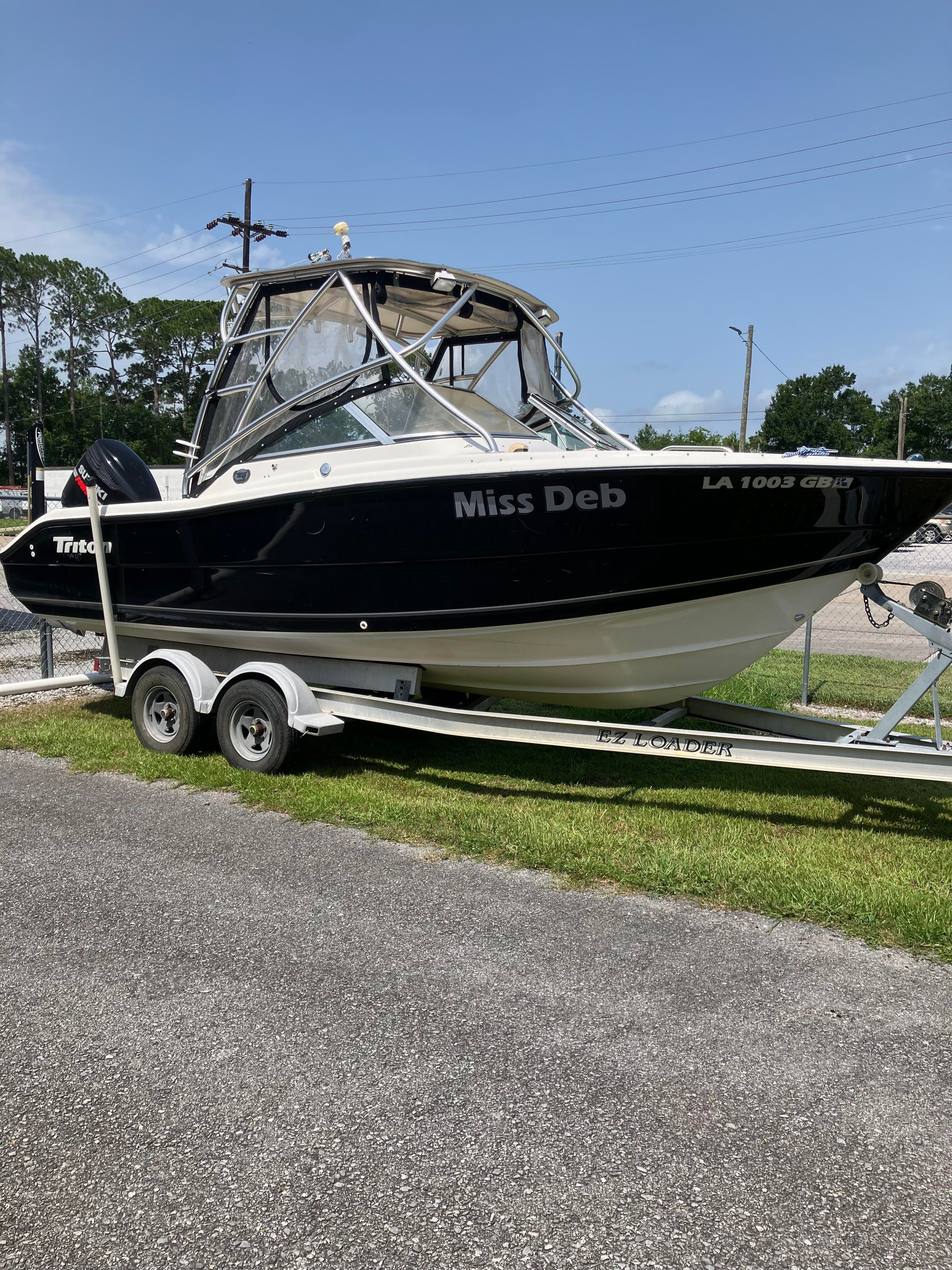 A 2007 Triton 225 DC boat on a trailer, featuring a black hull and cabin.