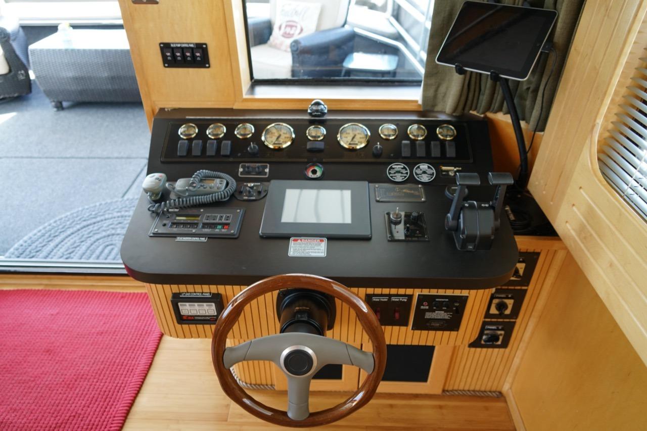 Control panel of a 2000 Stardust Cruisers 83'x17' houseboat with steering wheel and gauges.