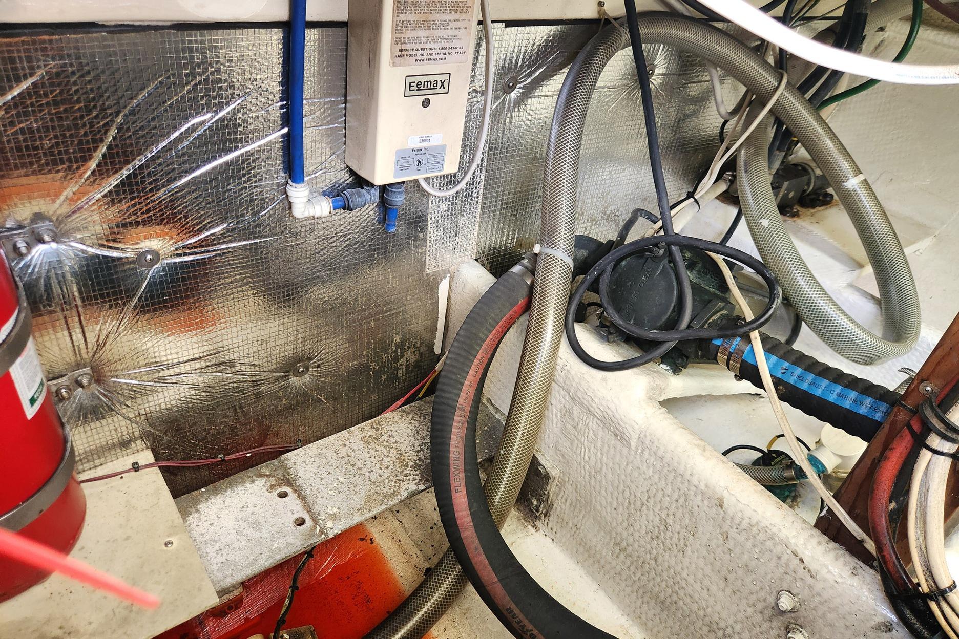 Engine room of 1987 Young Brothers Custom Sport Fish boat with hoses and equipment.