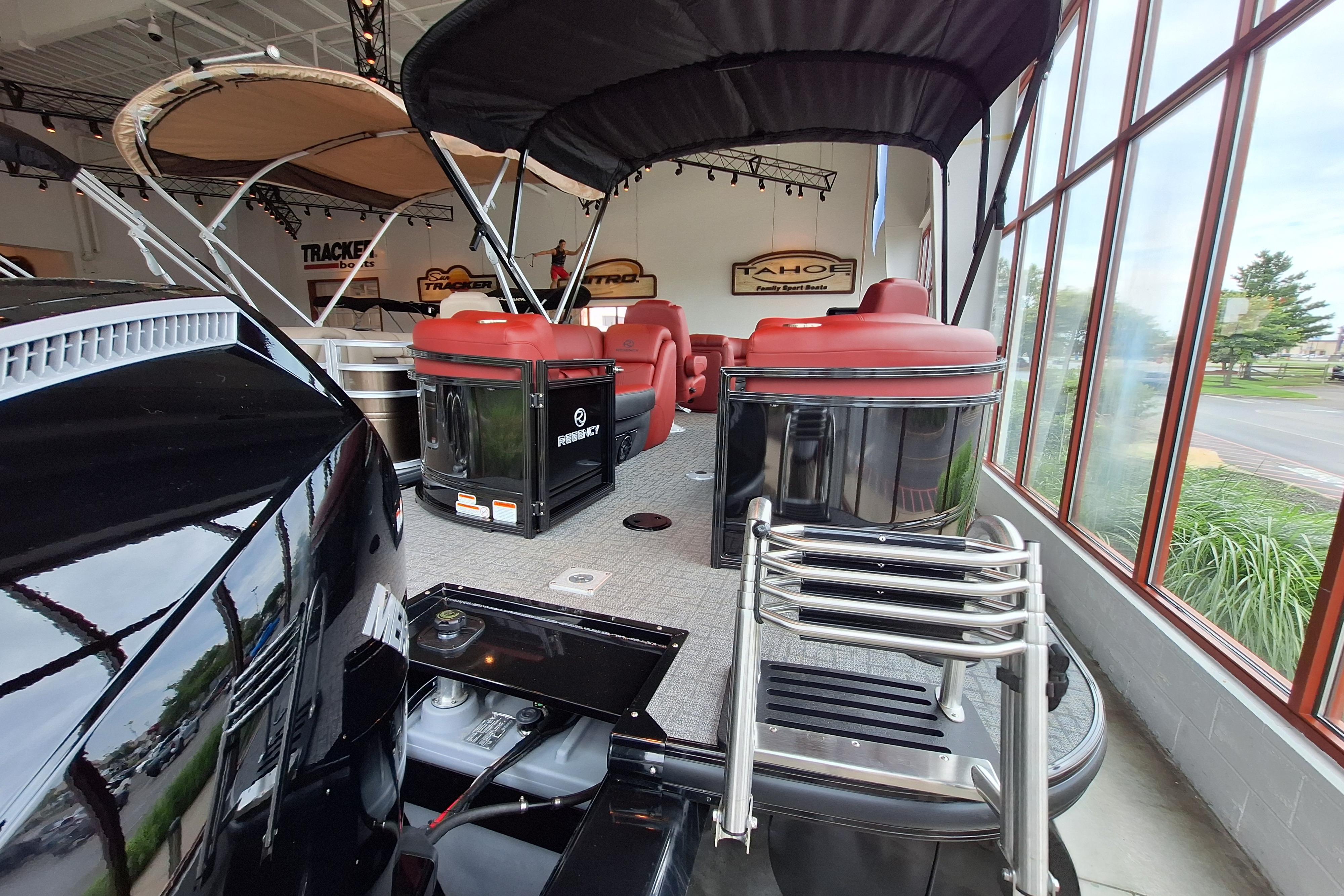 2026 Regency 230 DL pontoon boat with red seating, displayed indoors near large windows.