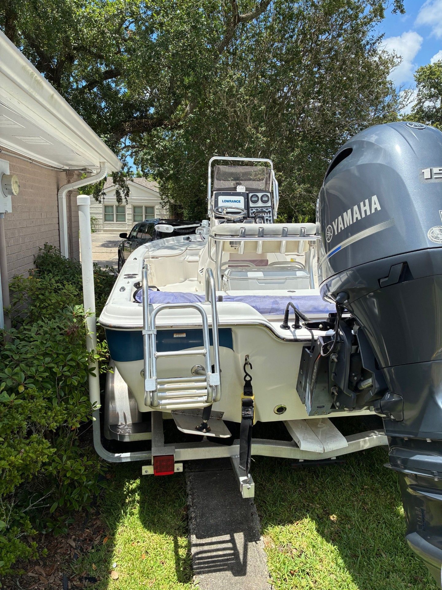 A 2018 Custom 2200 Pure Bay boat on a trailer beside a house.