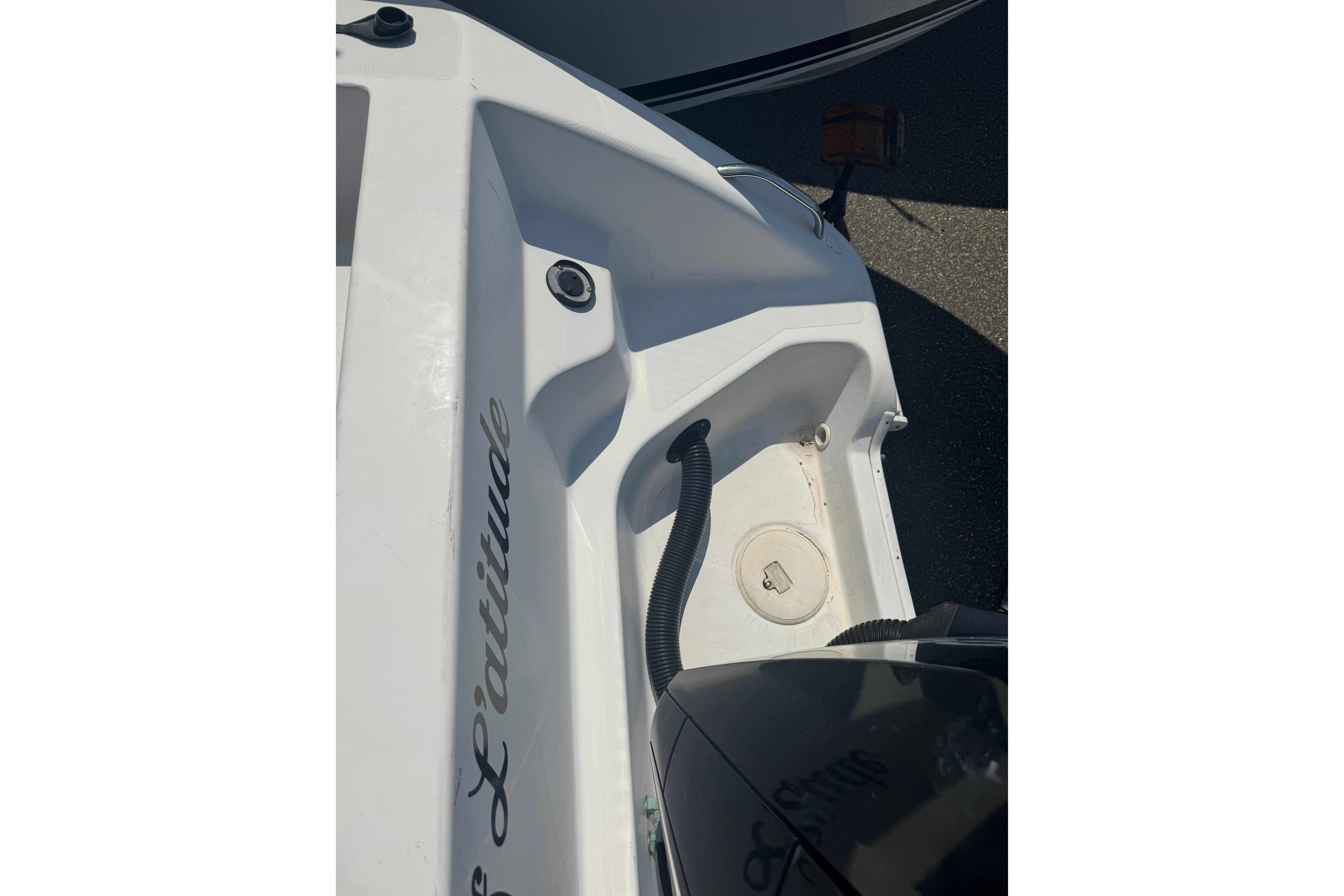 2002 Pro-Line 23 Sport boat deck with storage compartment and hose.