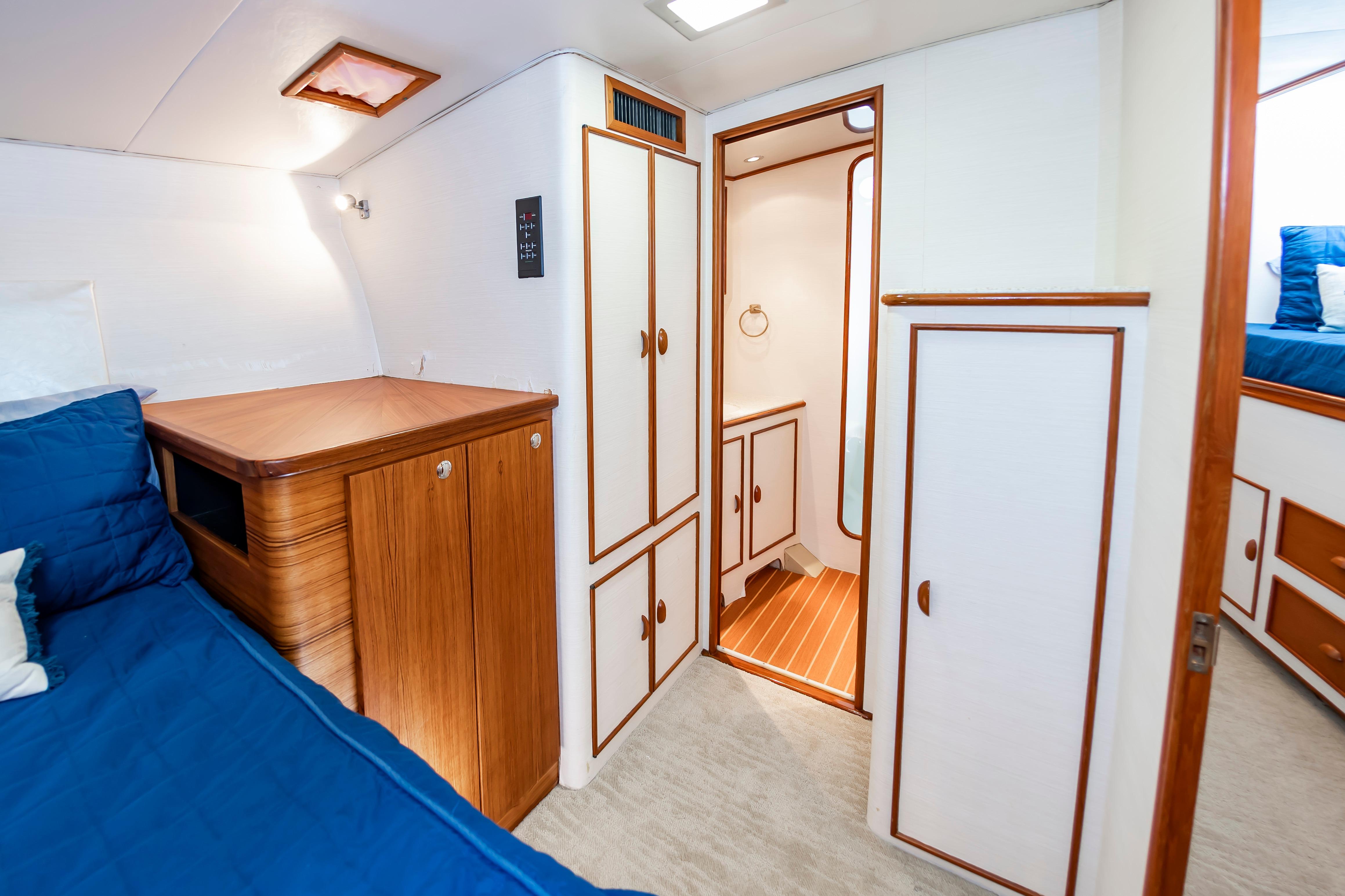 Interior of 1993 Custom Carolina Scarborough 56 Convertible yacht with wood accents and blue bedding.