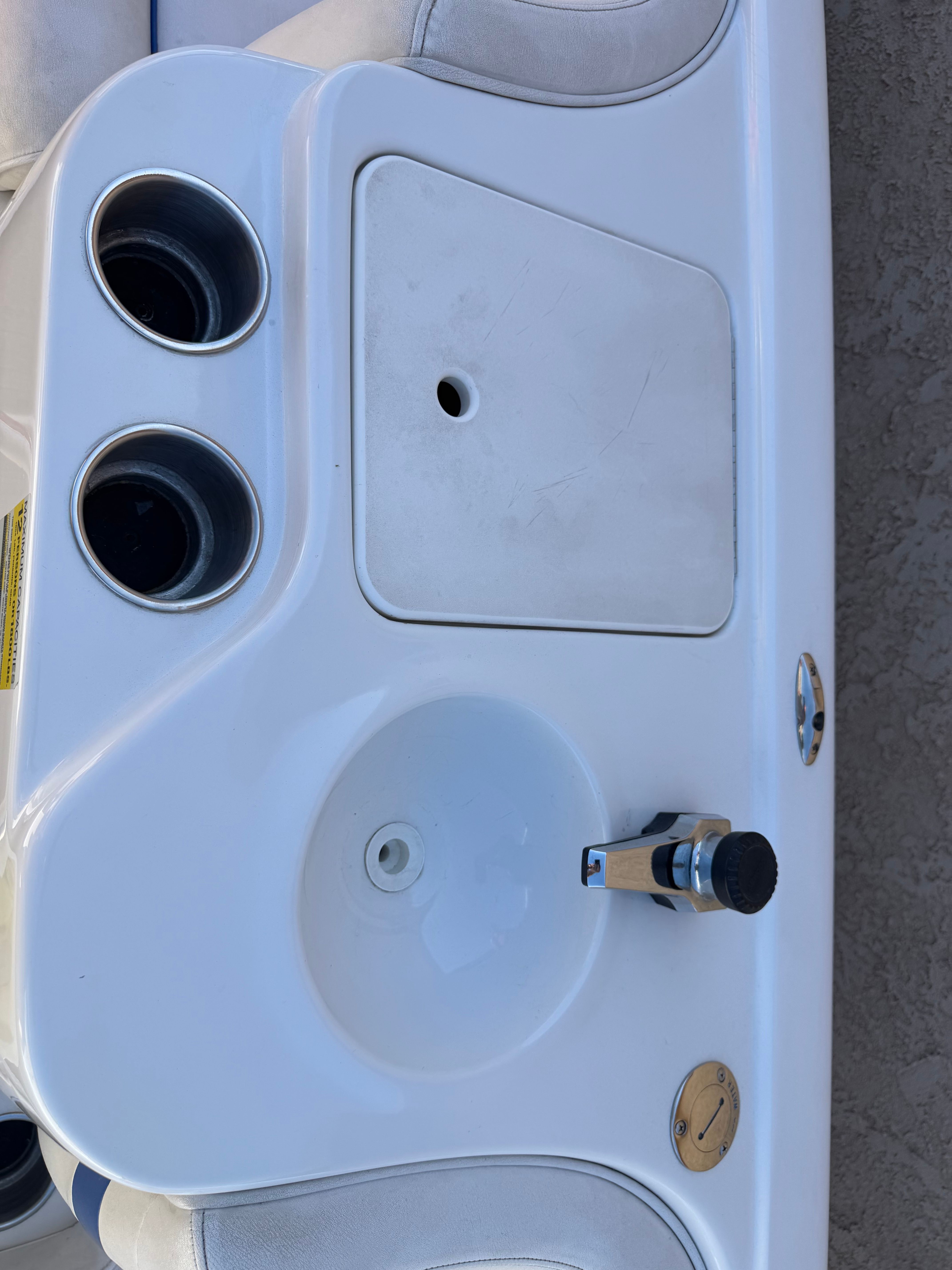 Close-up of a boat console area with cup holders and a faucet.