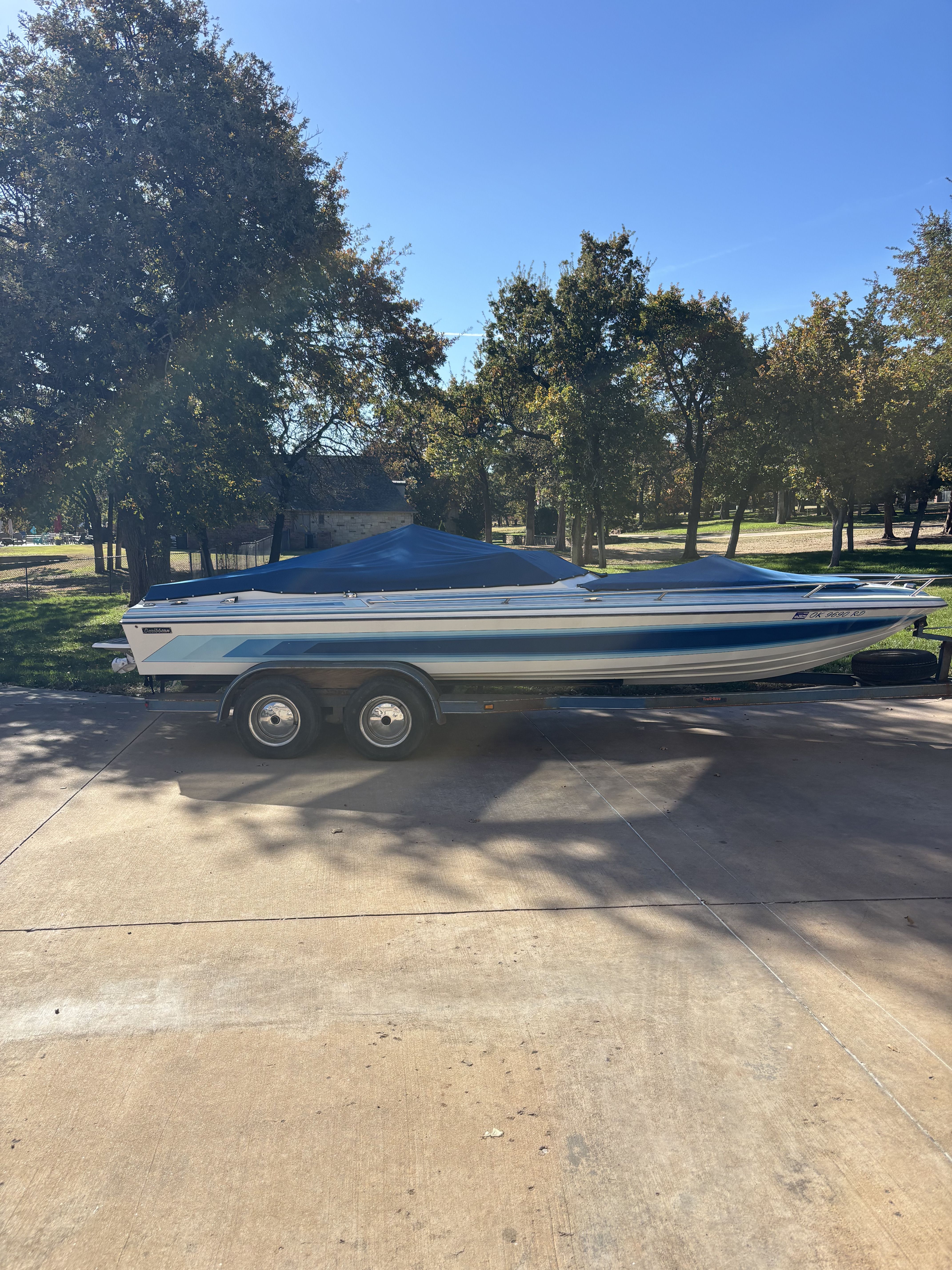 A 1984 Tahiti Carribean boat on a trailer in a sunny park setting.
