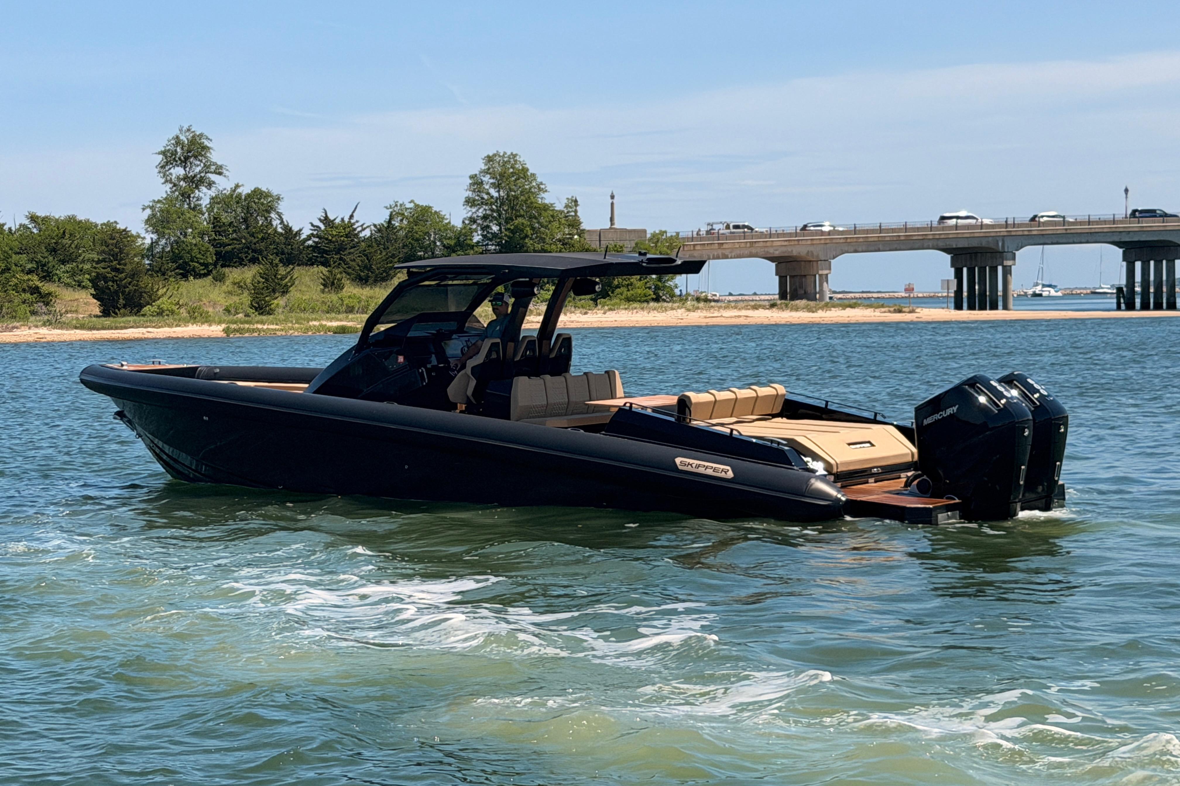 2023 Skipper-BSK 42NC boat cruising near a bridge on a sunny day.