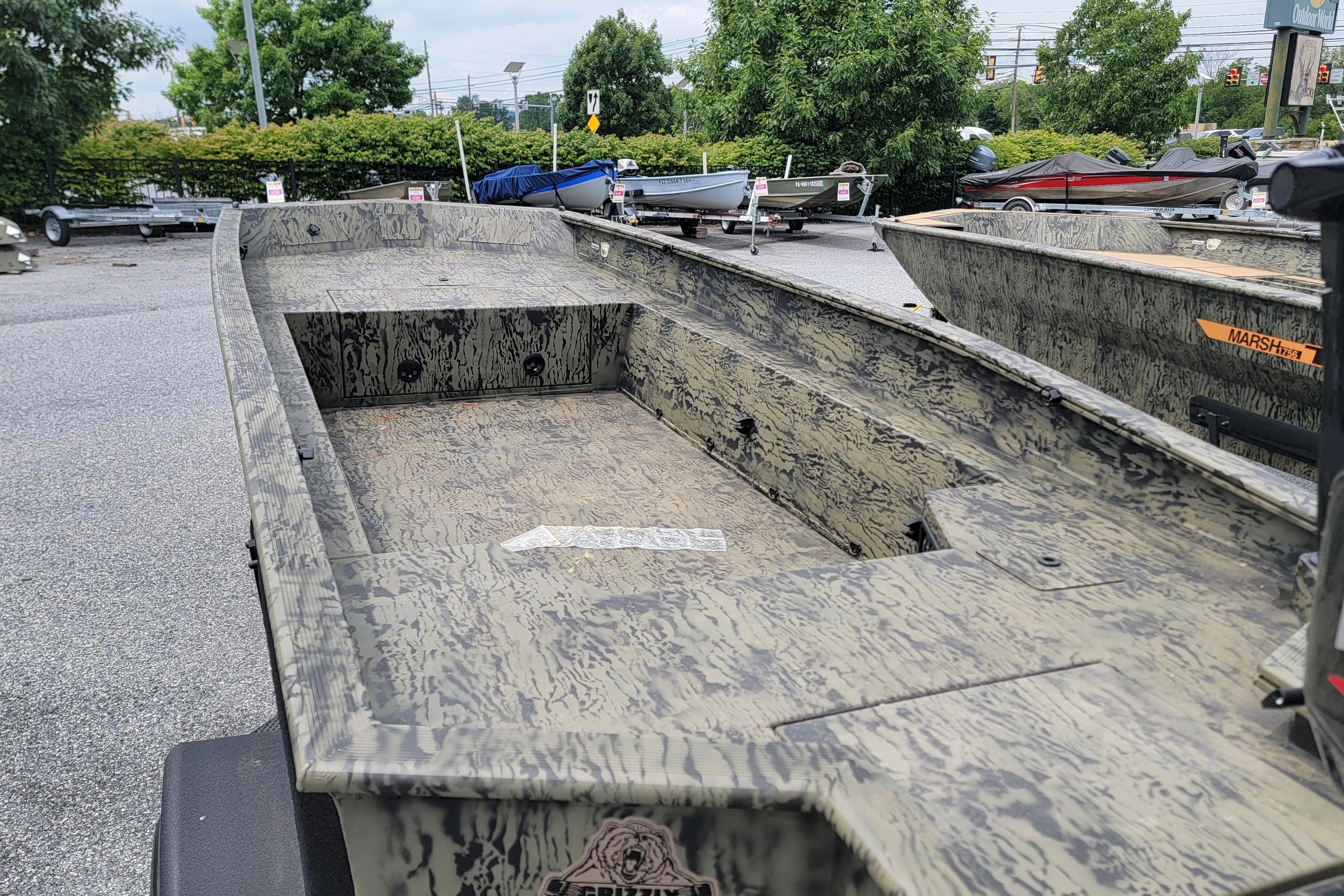2026 Tracker Grizzly 1650 T Prairie Wings Edition boat with camouflage design in a parking lot.