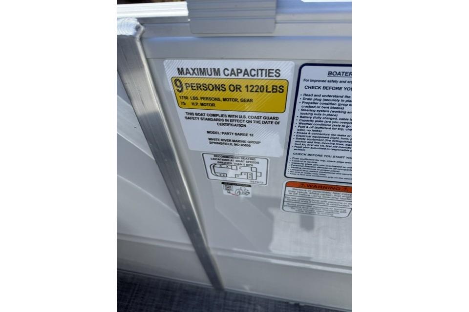 Capacity label on 2026 Sun Tracker Party Barge 18 DLX, showing 9 persons or 1220 lbs limit.