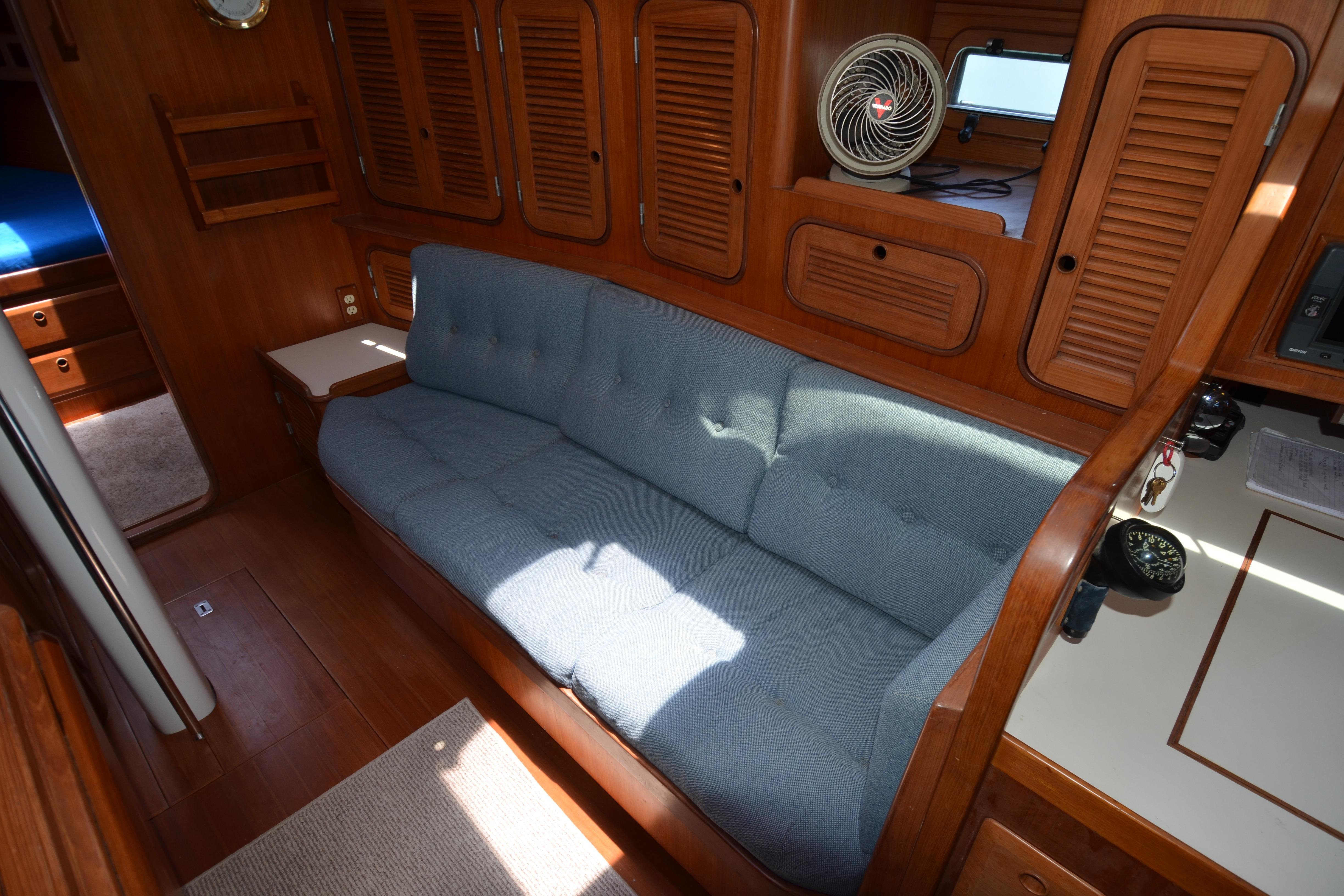 Interior of 1987 Norseman 400 yacht with blue sofa and wooden cabinetry.