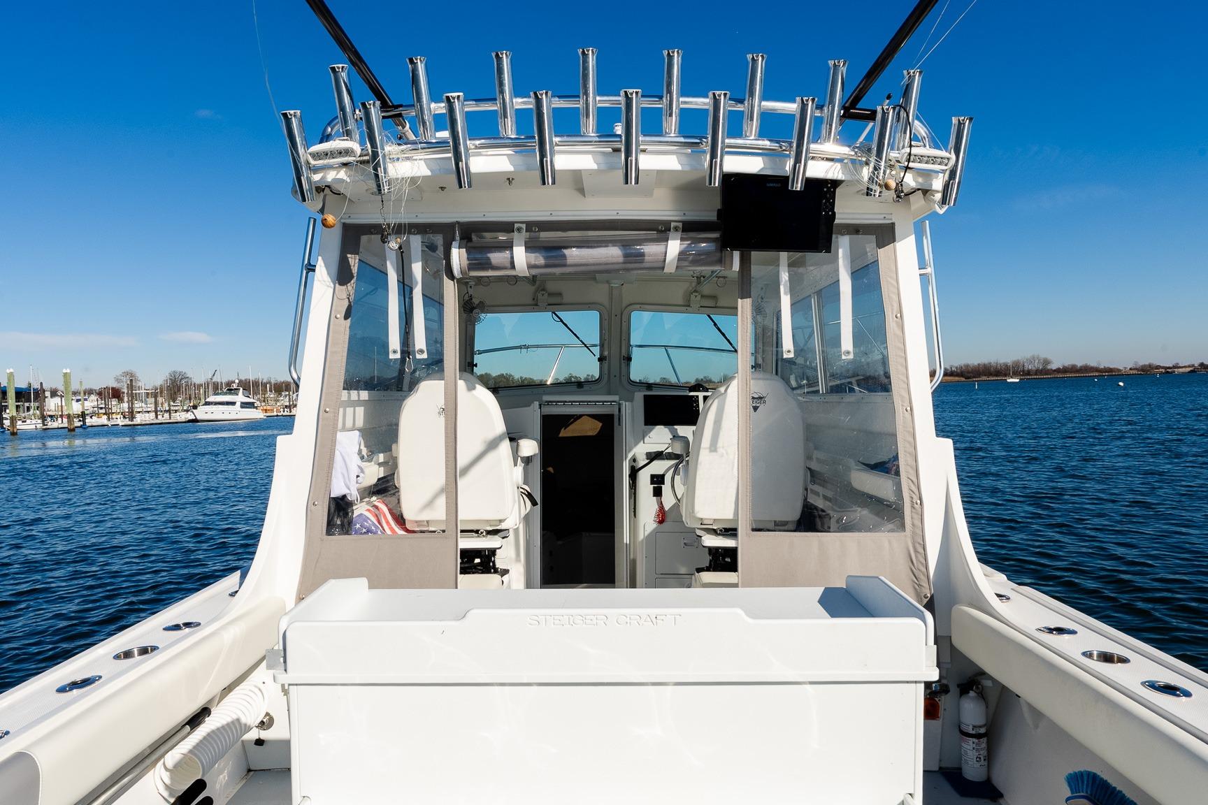 2024 Steiger Craft 31 Fisherman boat, rear view, docked on calm water under clear blue sky.