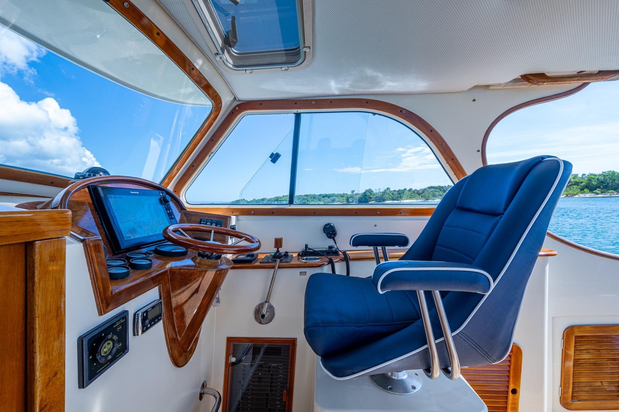 Interior of 2001 Hinckley Picnic Boat Classic with blue captain's chair and wooden dashboard.
