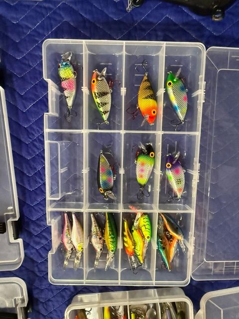 A fishing lure set in a transparent box with various colorful lures.