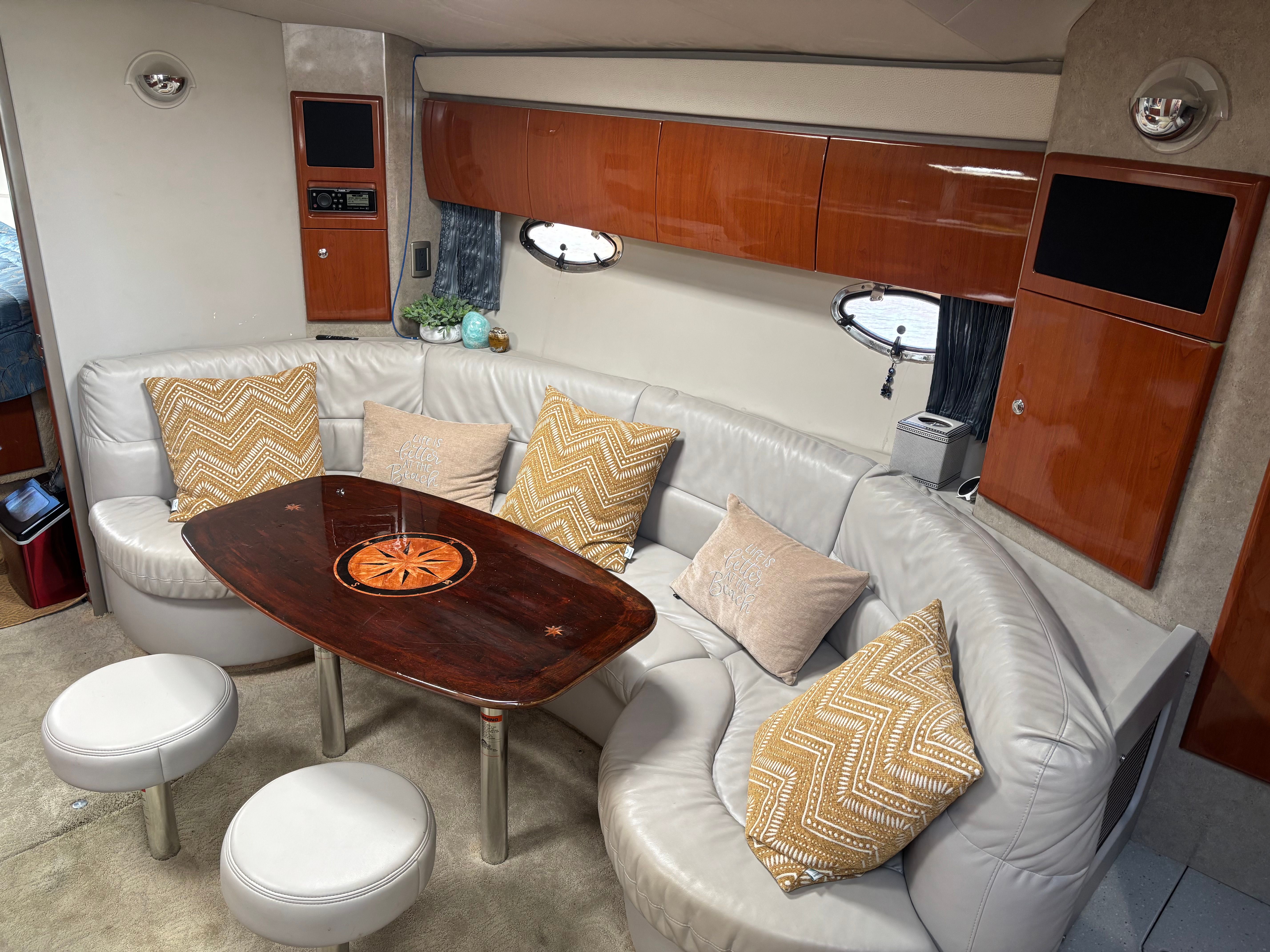 Interior of a luxury yacht with white leather sofa and wooden table.