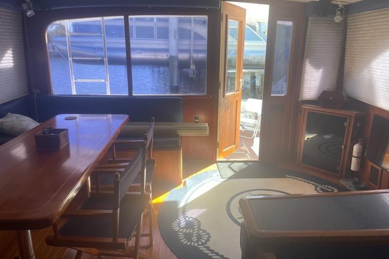 Interior of 1987 Topaz 44 Flybridge yacht with wooden table and nautical decor.