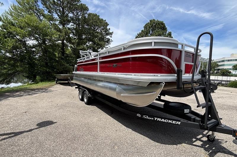 2026 Sun Tracker SportFish 20 DLX pontoon boat on trailer, parked outdoors.