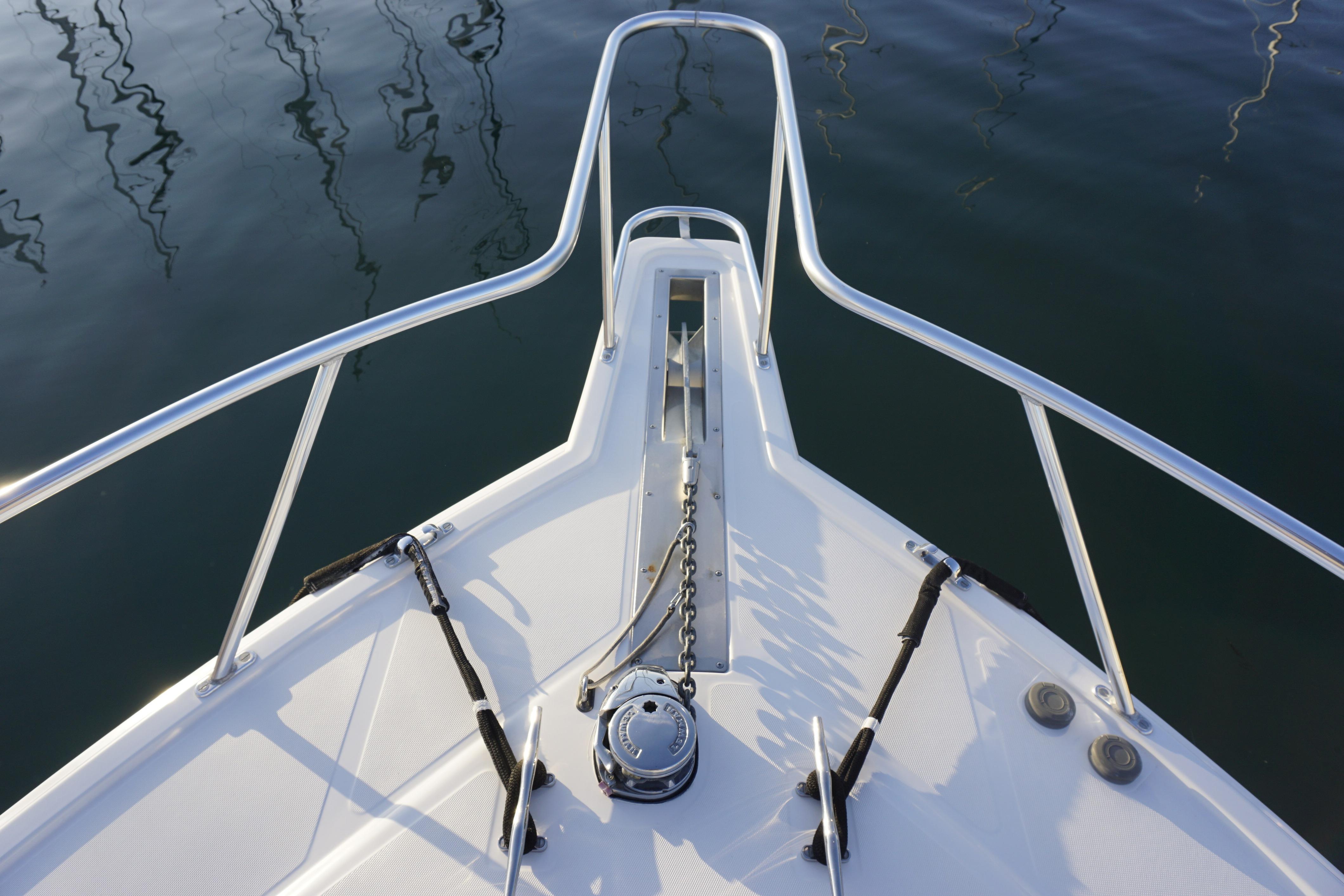 Bow of 2005 Cabo 35 Express boat with anchor chain and calm water reflection.