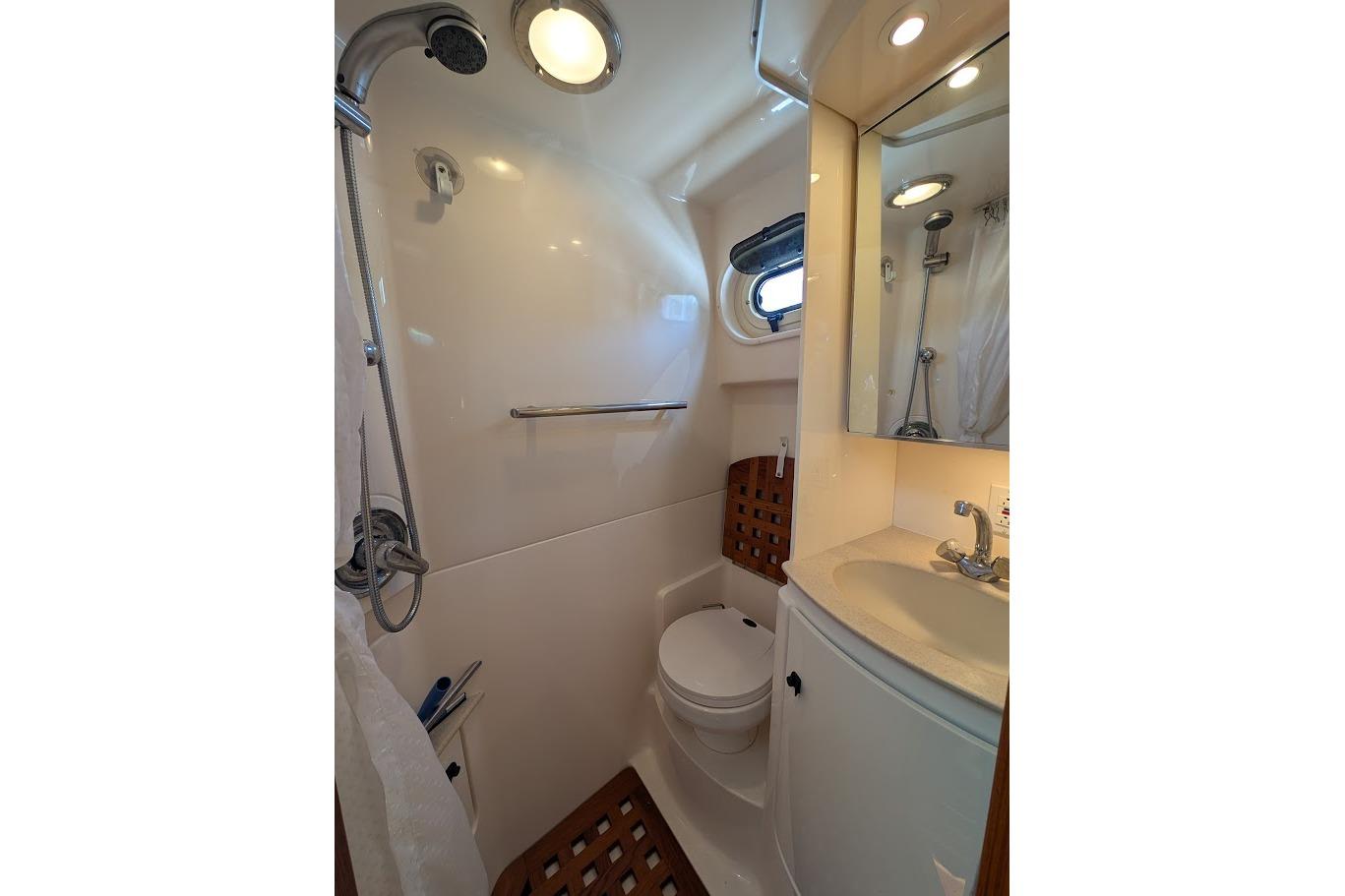 Bathroom interior of 2000 Pursuit 3400 Express boat, featuring shower, sink, and toilet.