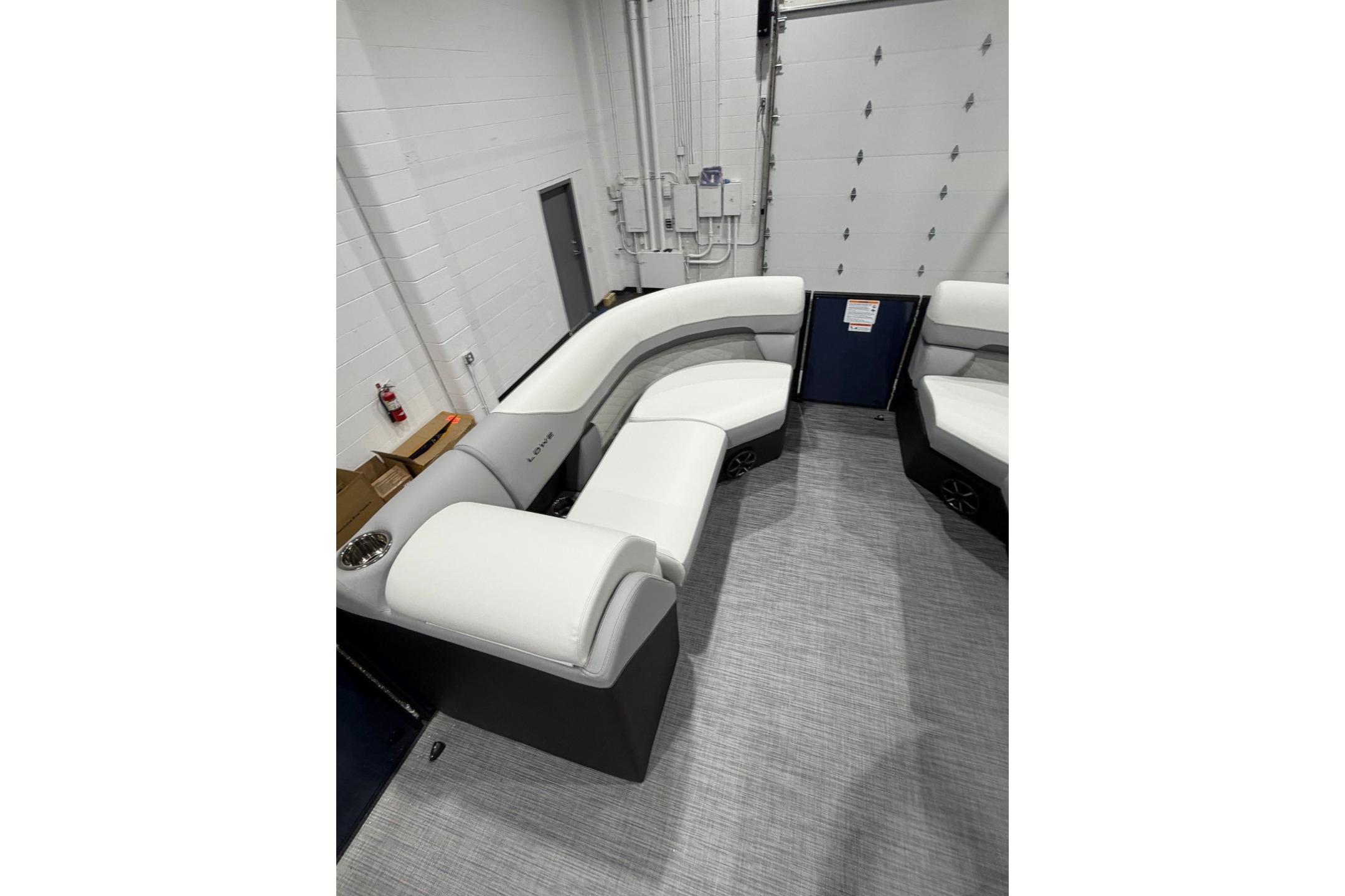 2026 Lowe SS 230 WT boat interior with white cushioned seating in a showroom.