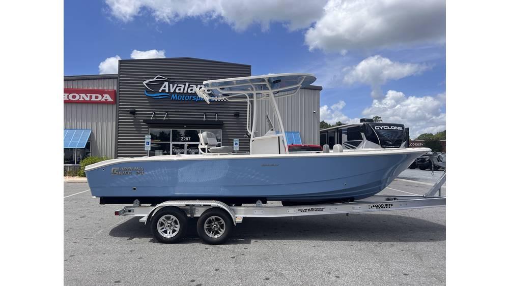 2025 Carolina Skiff 24 Ultra Elite boat on trailer, parked outside dealership.