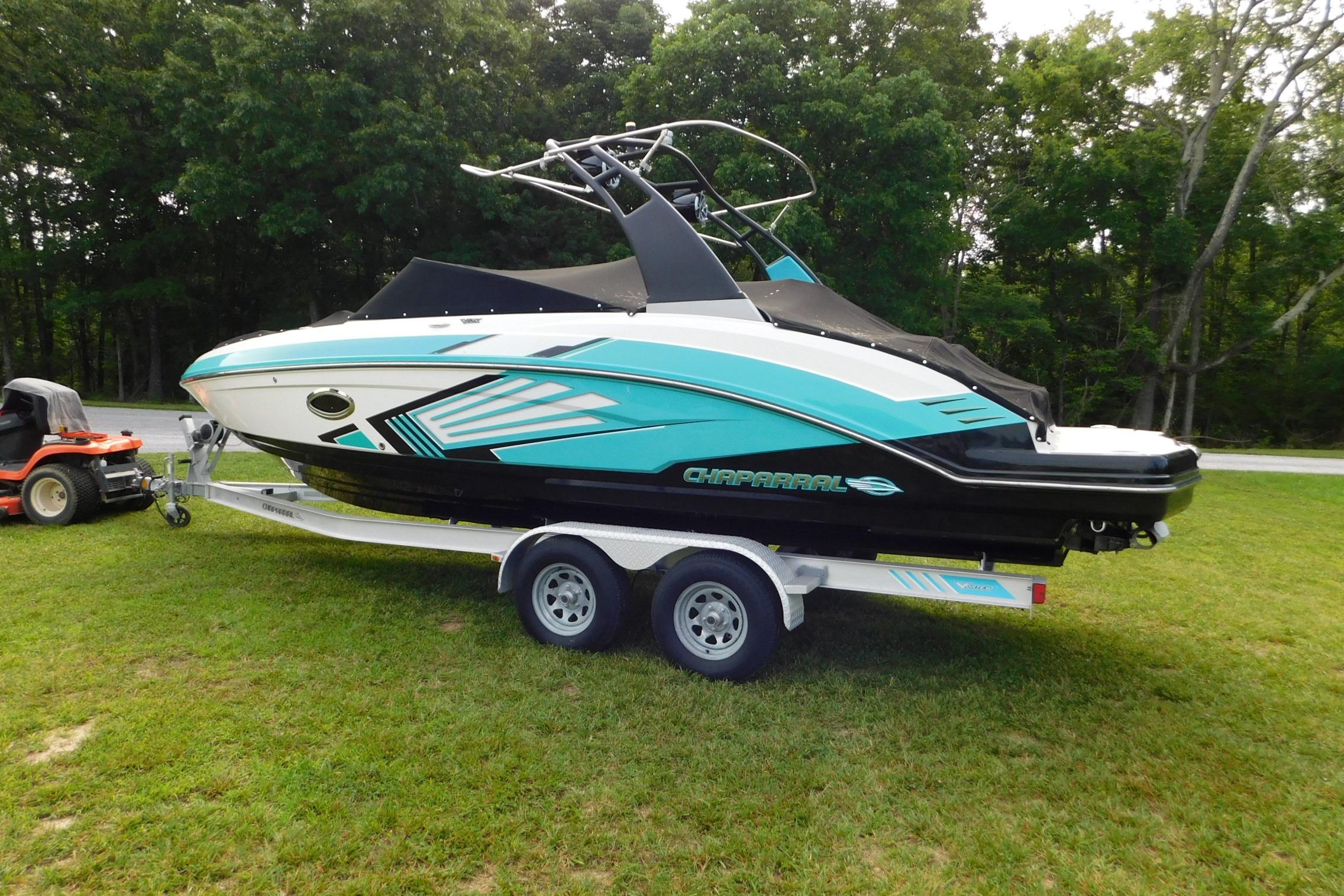 2016 CHAPPARRAL 243 boat on trailer, parked on grass with trees in background.