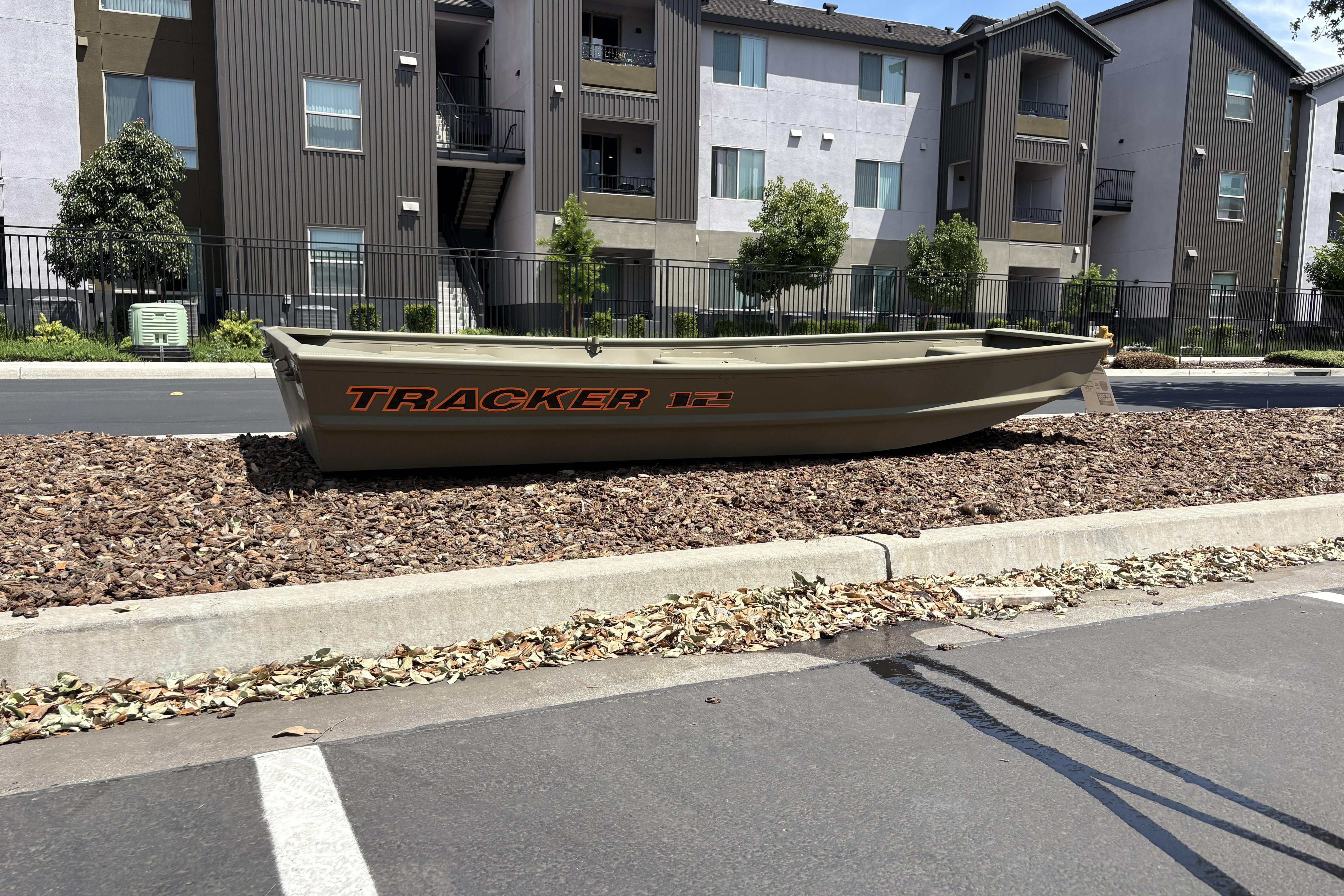 2026 Tracker Grizzly 12 Jon boat displayed outdoors near residential buildings.
