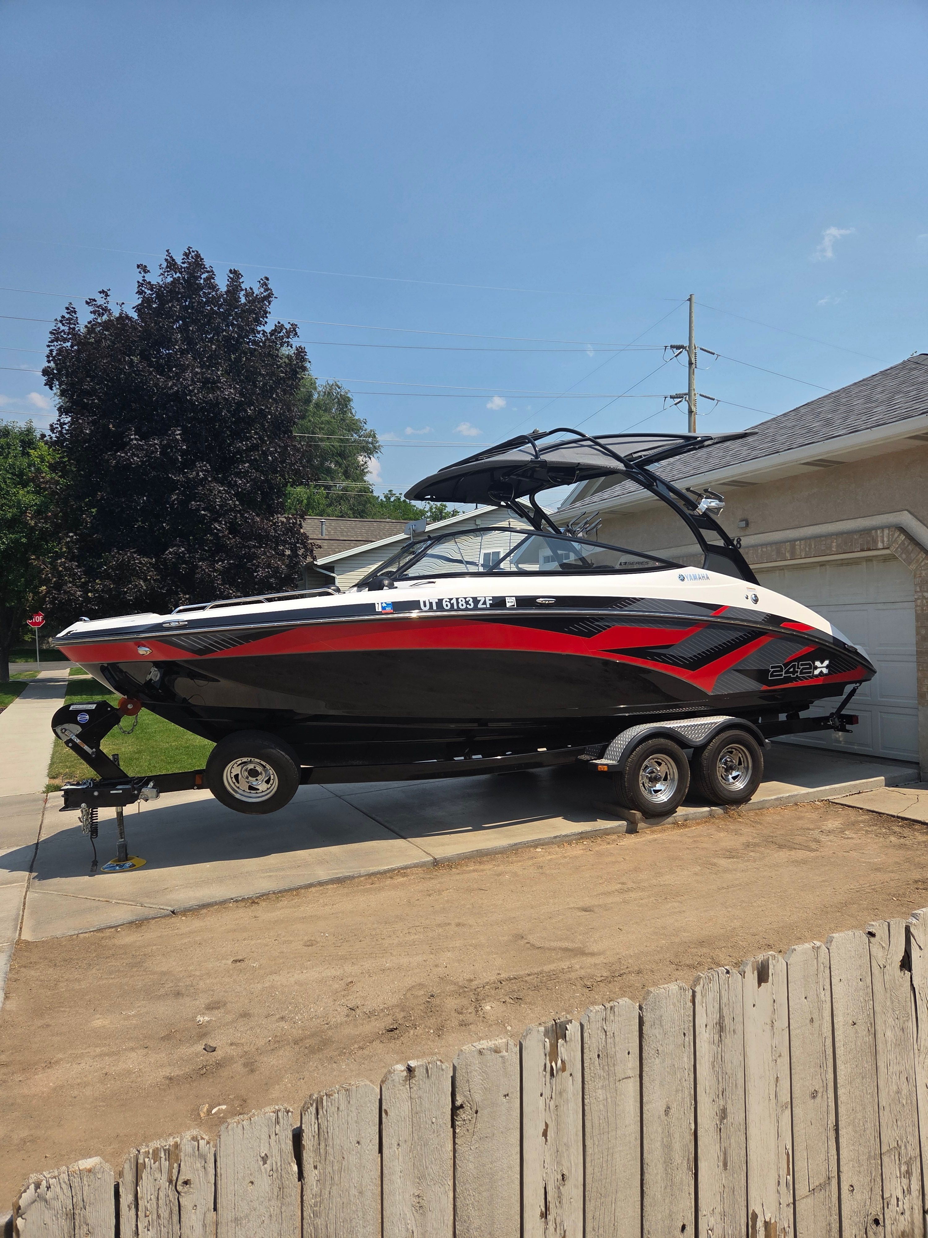 A 2016 Yamaha 242X E-Series boat on a trailer in a driveway.