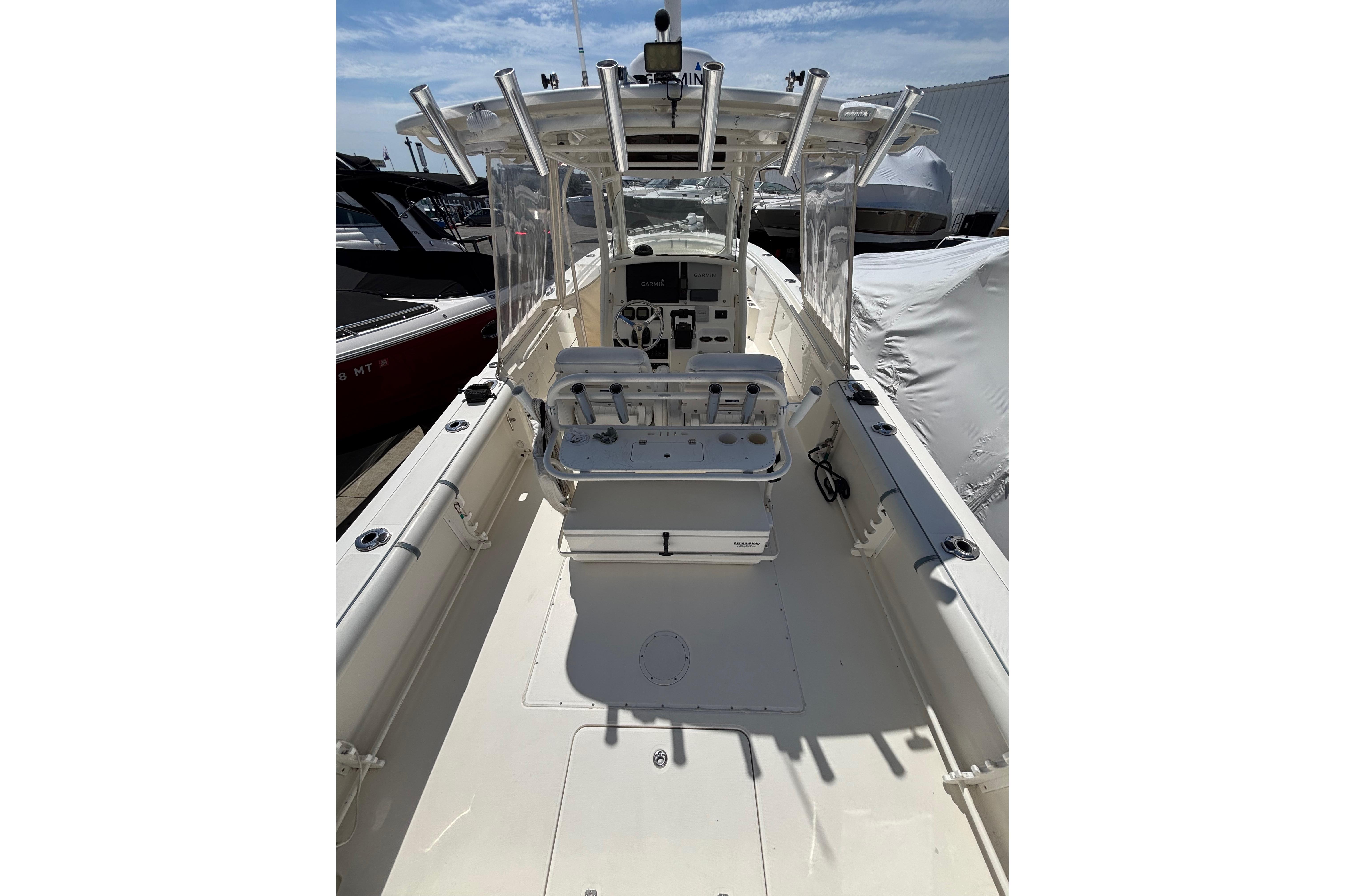 2006 Edgewater 318CC boat interior with helm, seating, and fishing rod holders under a clear sky.