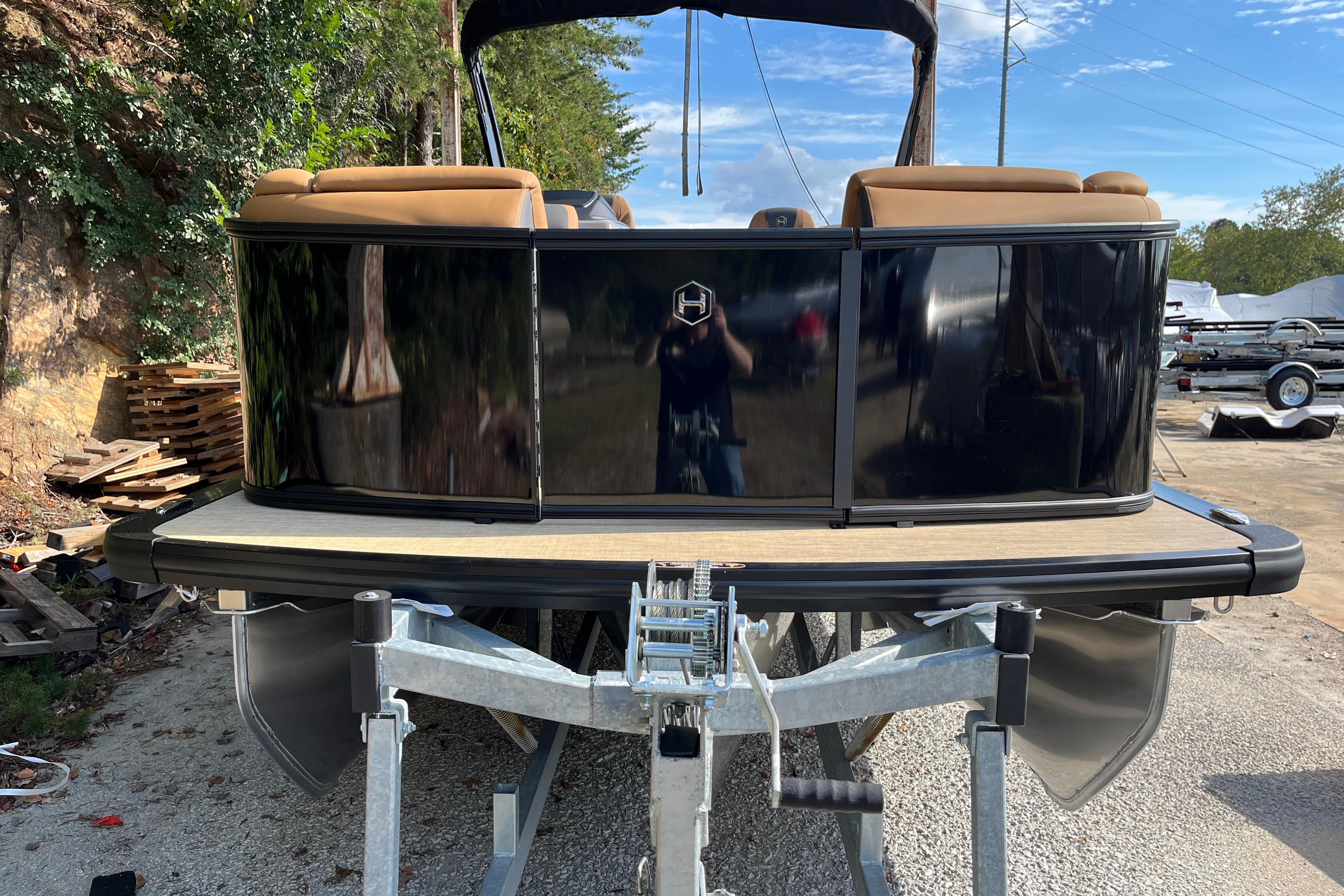 2025 Harris Sunliner 250 pontoon boat on trailer, featuring sleek black exterior and tan seating.