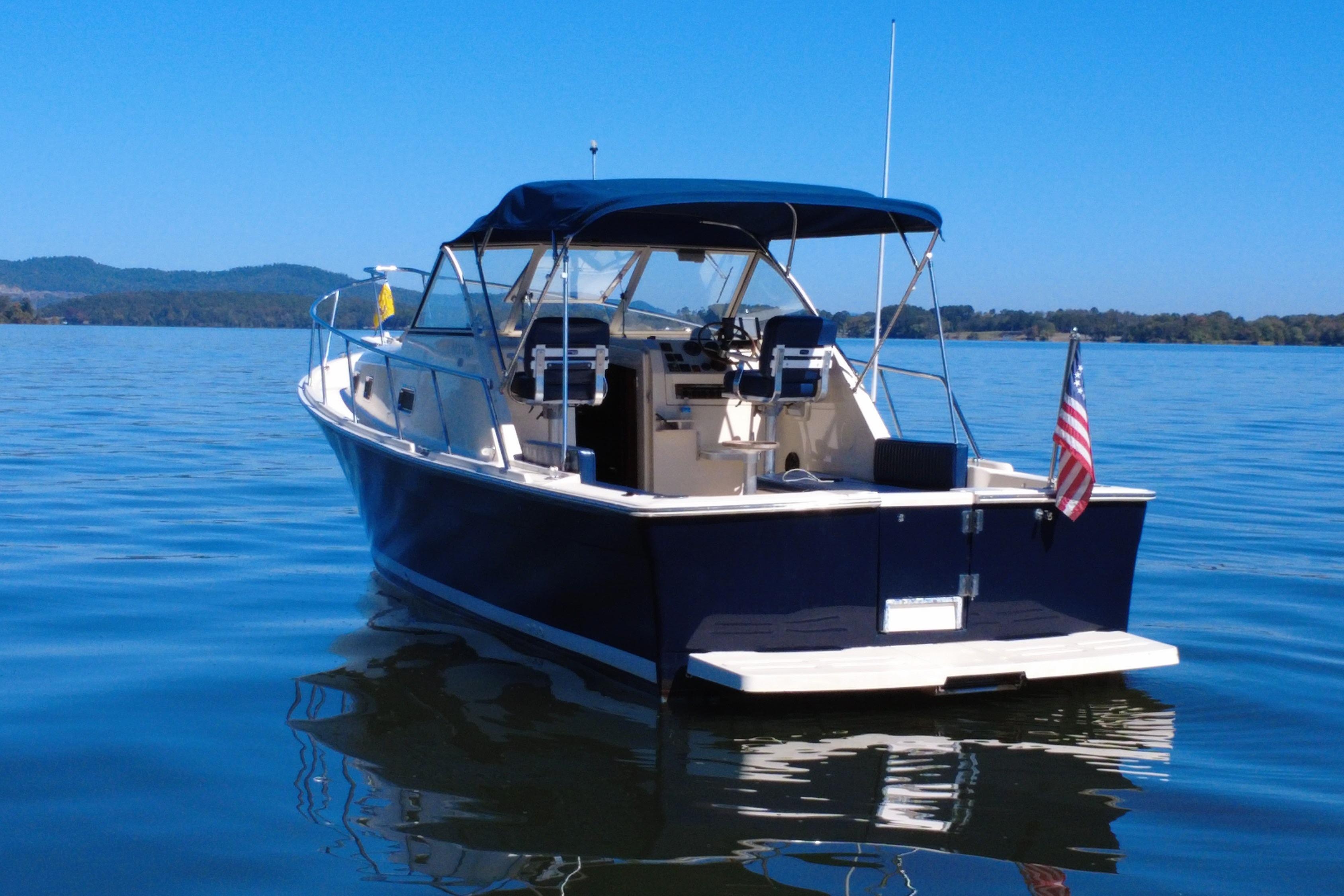 2003 Mainship Pilot 30-II boat on calm water with American flag.