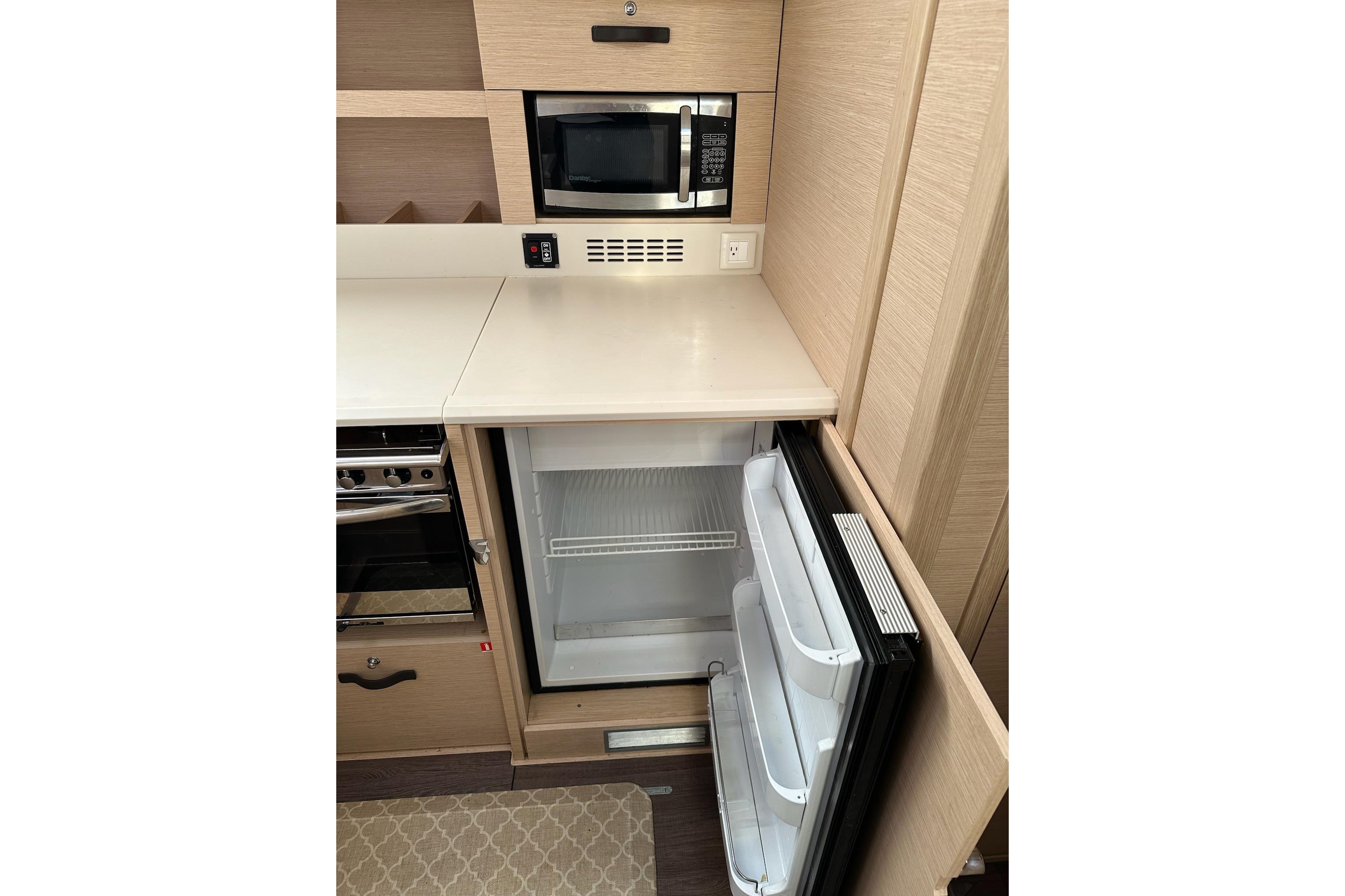 Modern kitchen area in a 2018 Jeanneau 51 yacht with fridge and microwave.