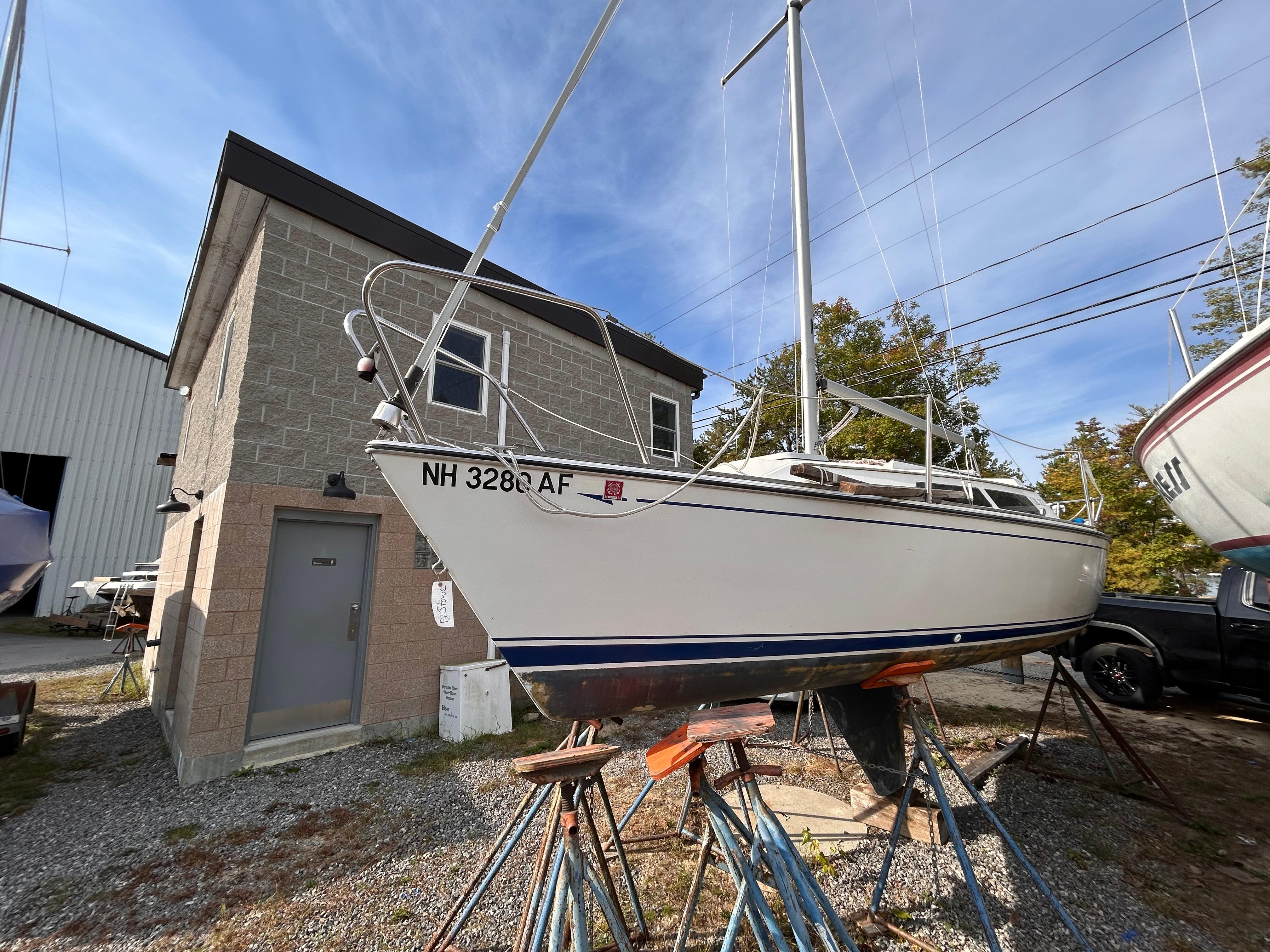 1986 CAL 22 sailboat on stands near a building, ready for maintenance.