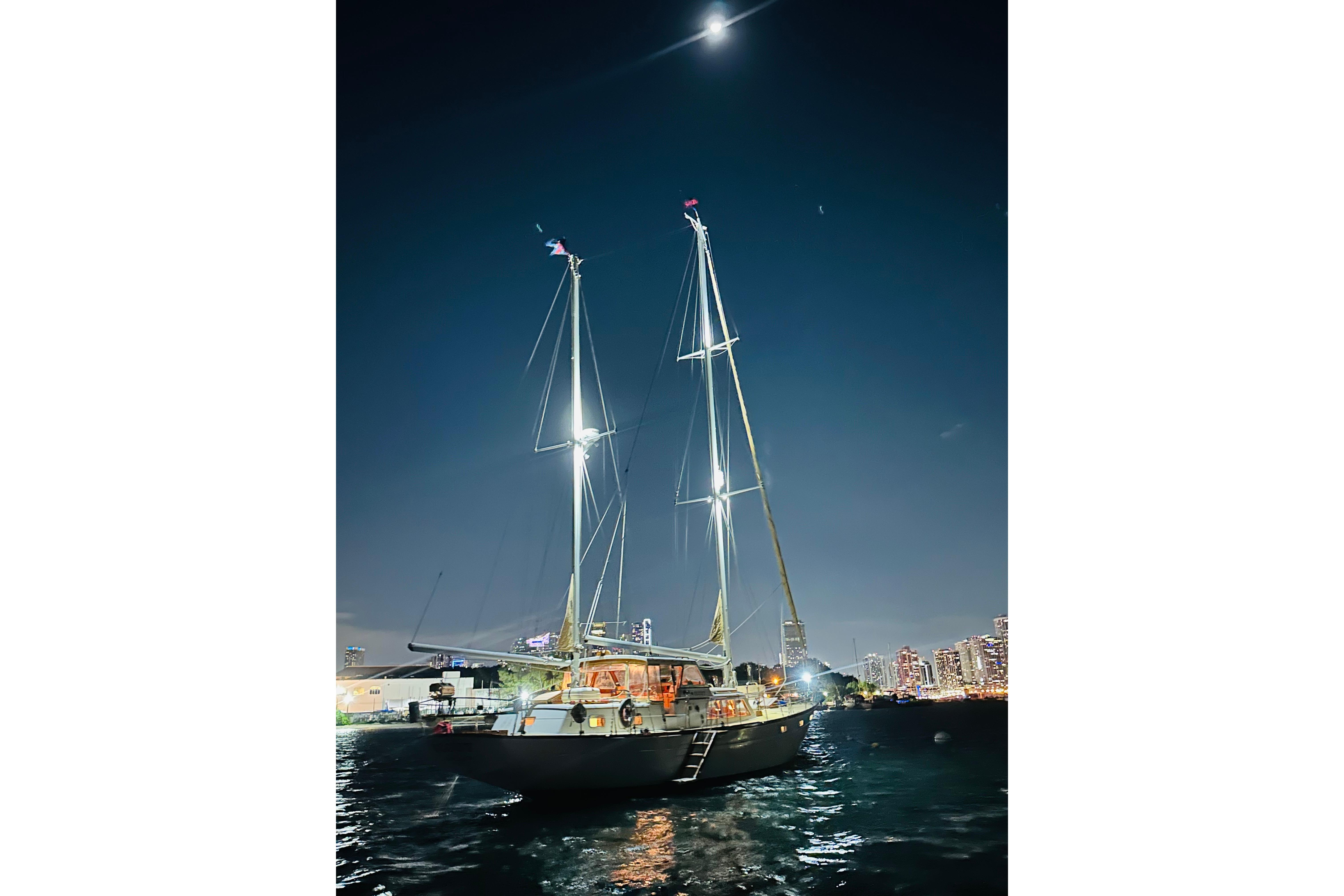 Sailboat Alden Boothbay Explorer 1971 illuminated at night on calm waters.