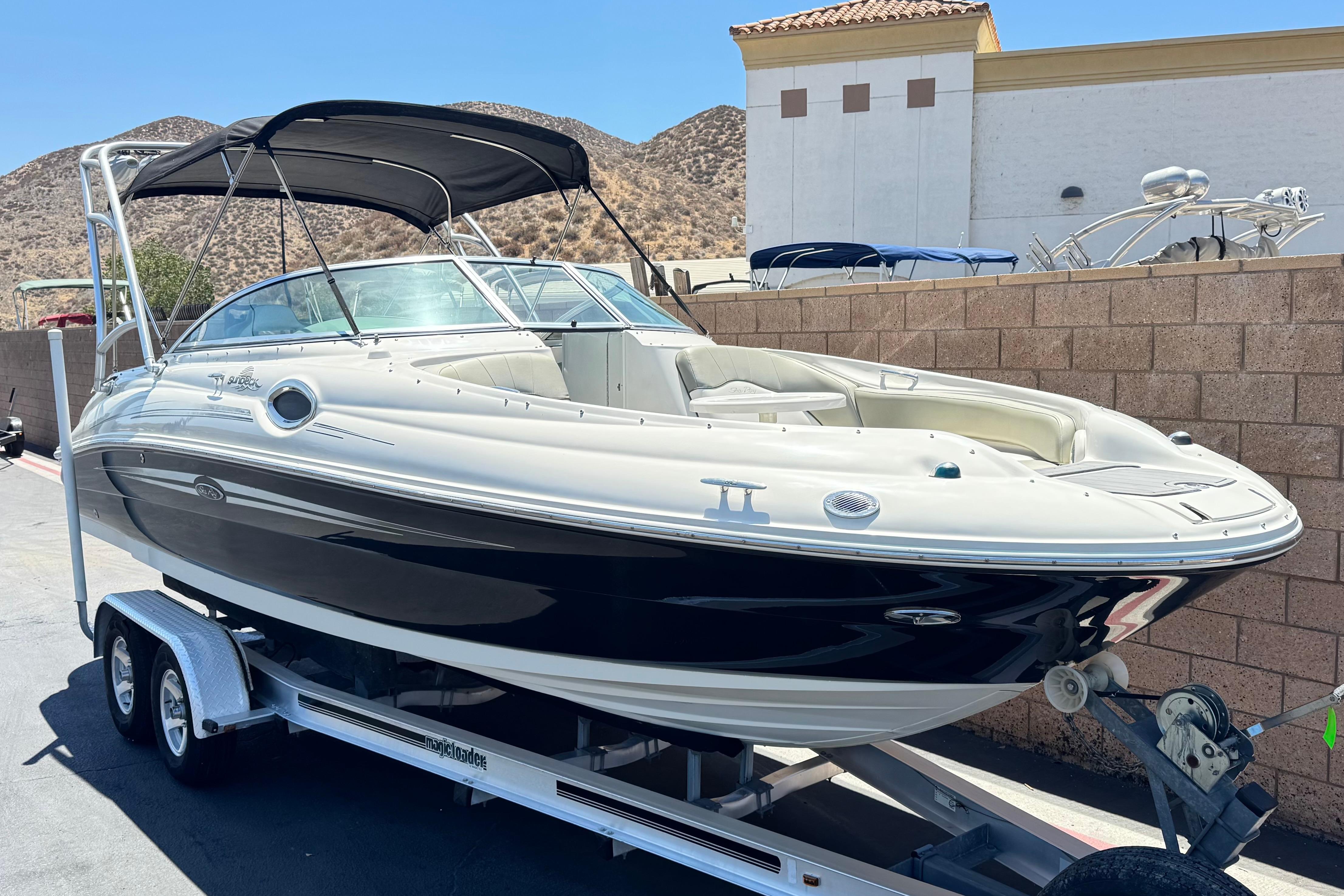 2007 Sea Ray 240 Sundeck boat on trailer, parked outdoors with hills in background.