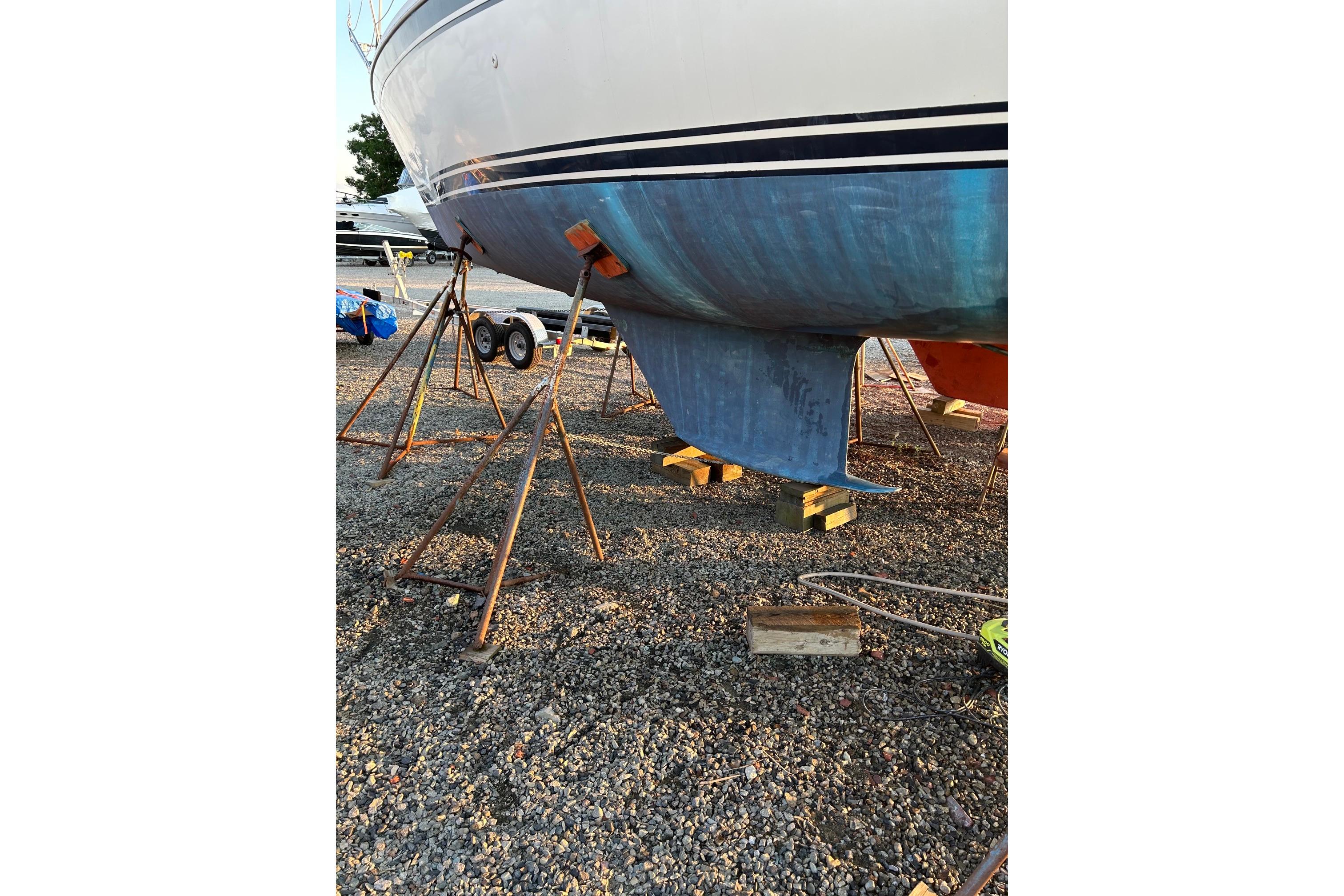 1987 Ericson 38-200 sailboat on stands, gravel ground, visible keel.