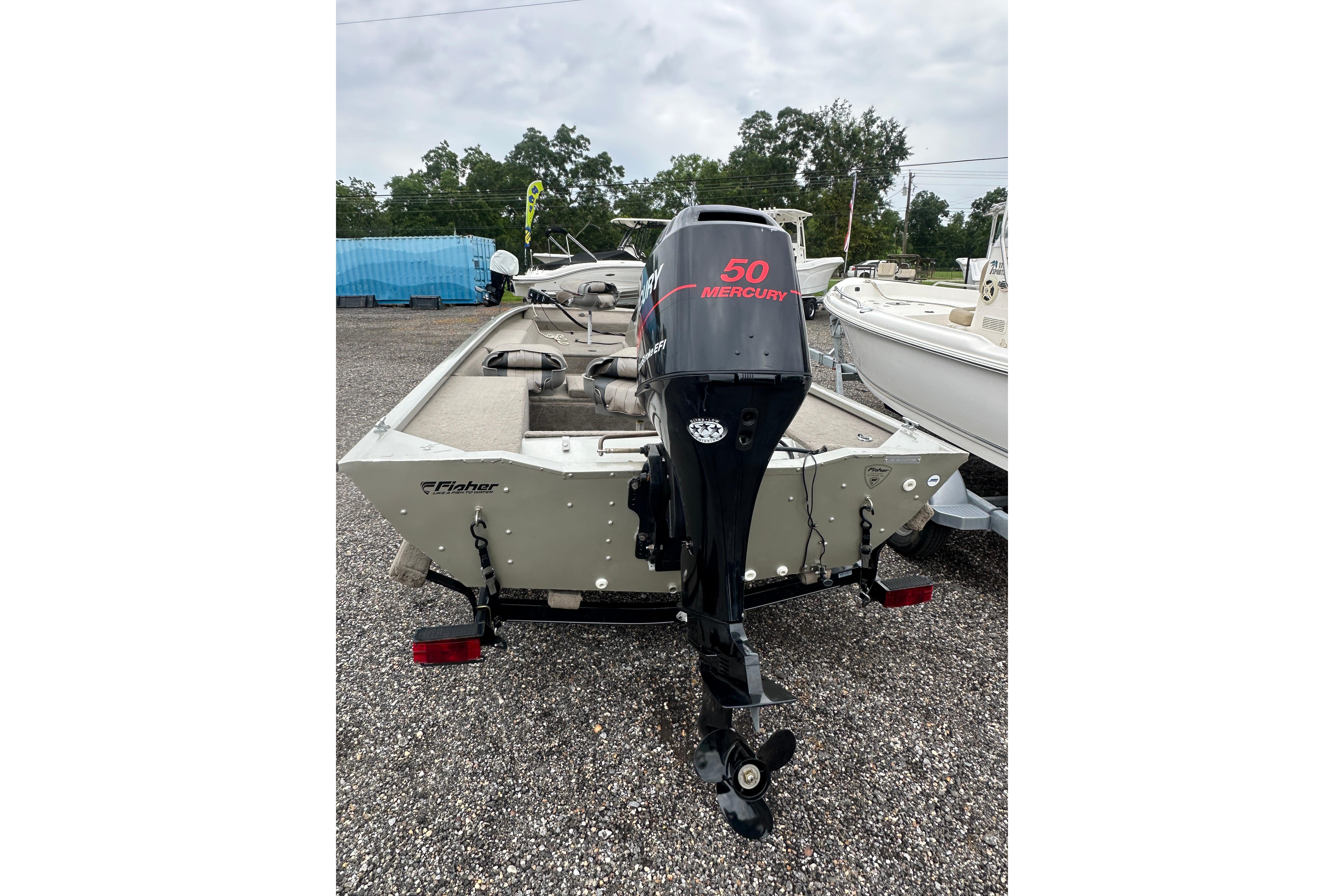 2002 Fisher 1710 boat with Mercury 50 outboard motor, parked on gravel.