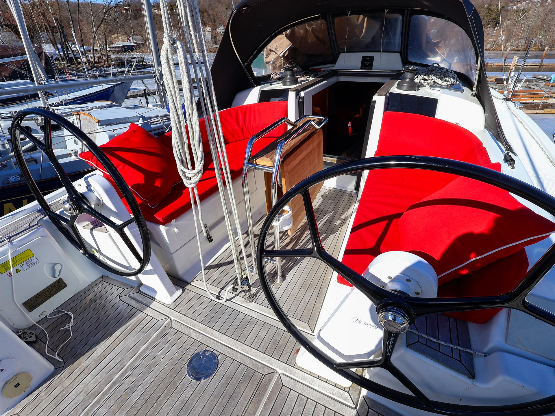2018 Hanse 315 yacht cockpit with dual steering wheels and vibrant red seating.