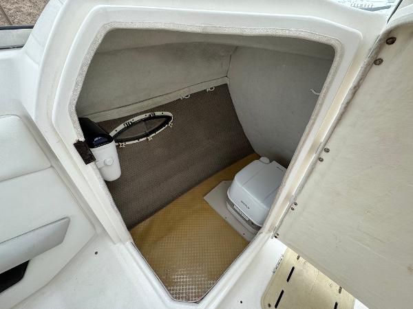 2006 Larson LXi 248 boat cabin with portable toilet and storage space.