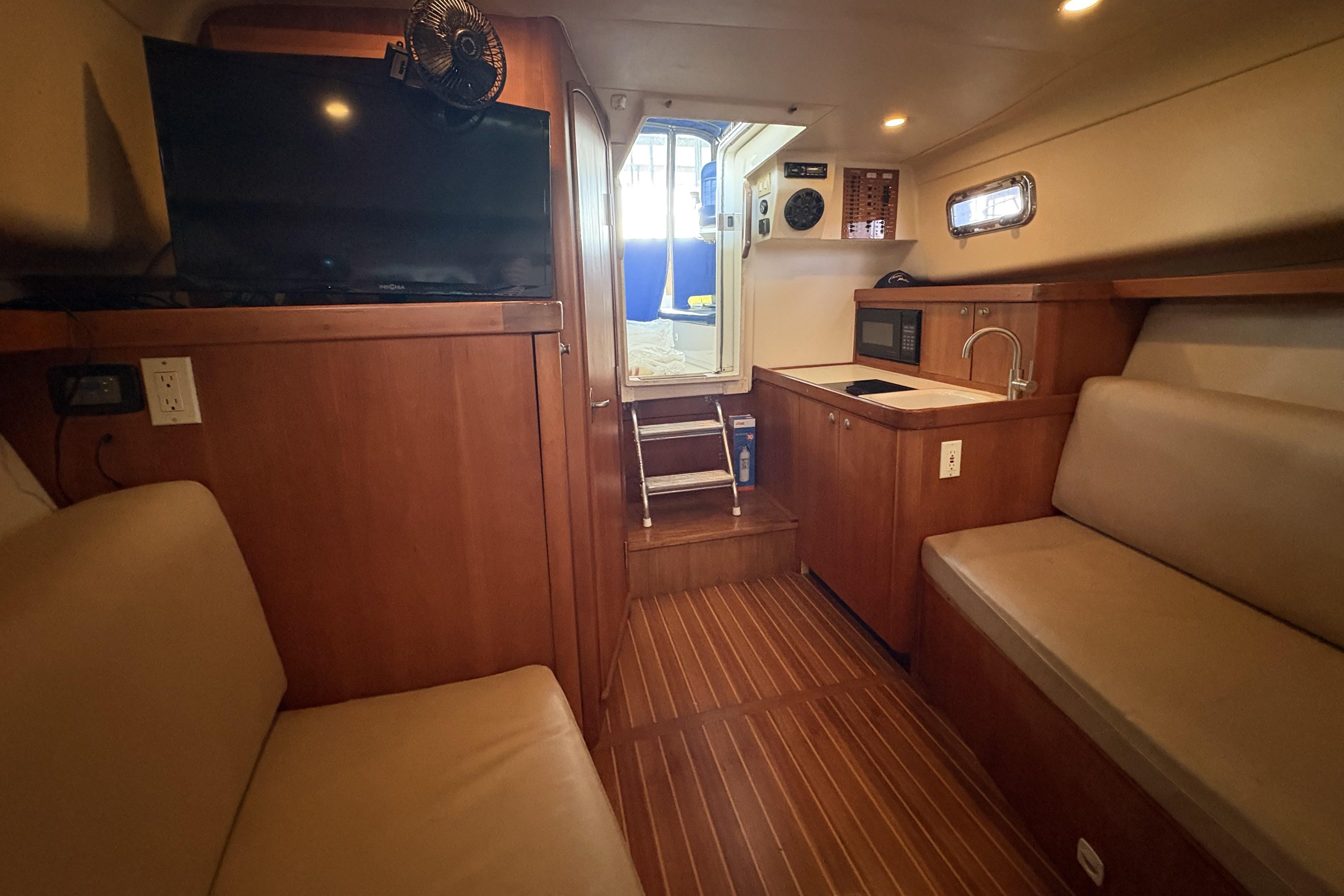 2003 Mainship Pilot 30-II interior with wood finish, kitchenette, and seating area.