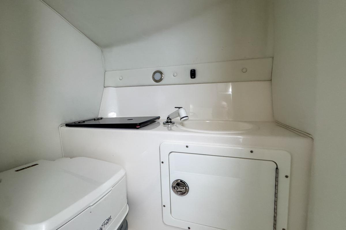 2022 Velocity 290sc boat interior with compact bathroom and sink area.
