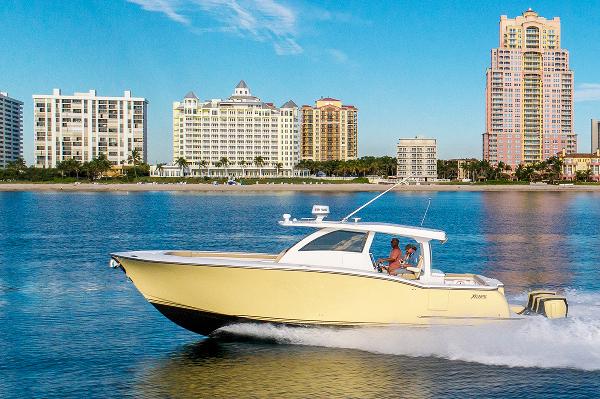 2019 Altima 38 Xcape boat cruising on water with city skyline in background.