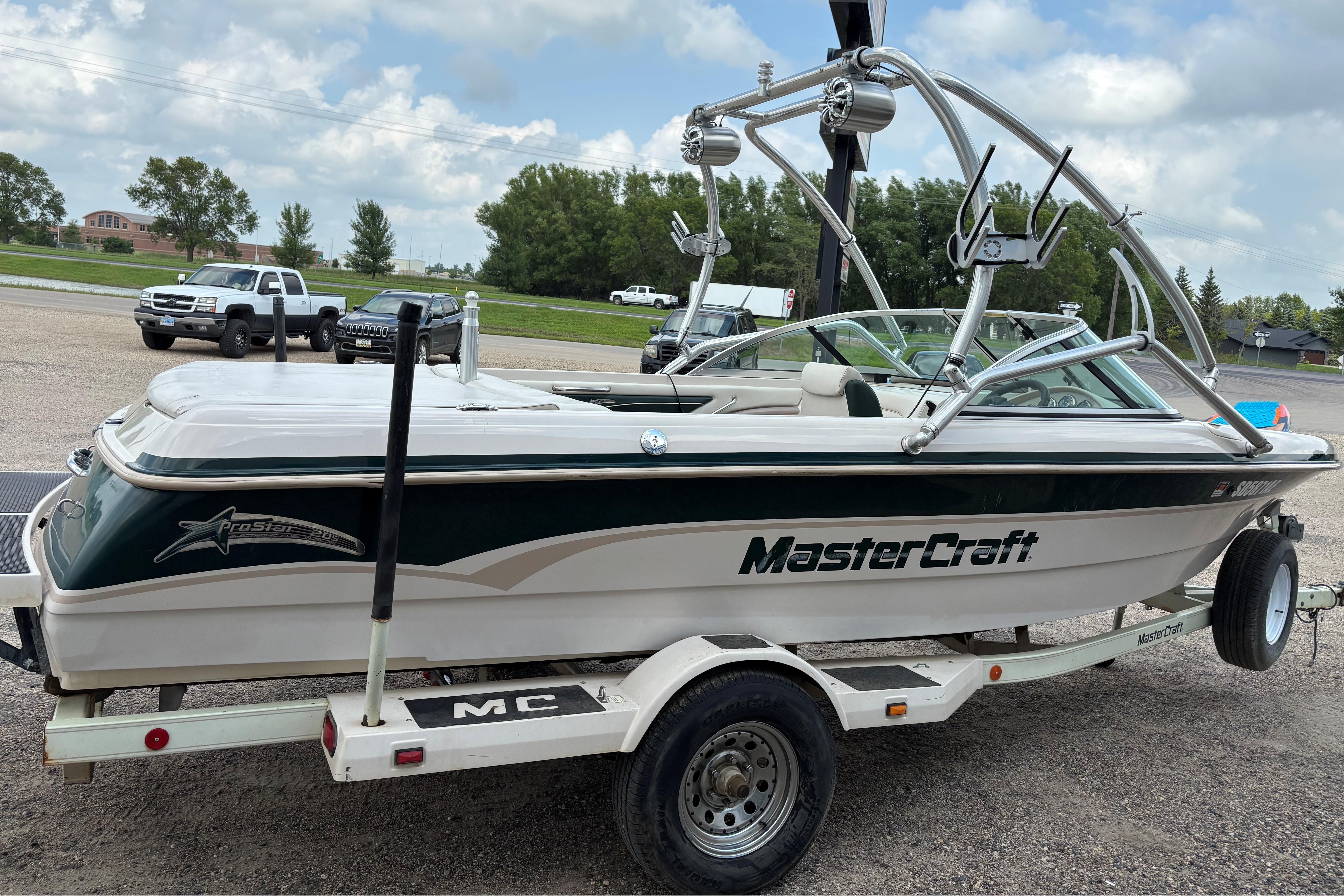1999 MasterCraft 205 PRO STAR boat on trailer, parked outdoors under cloudy sky.