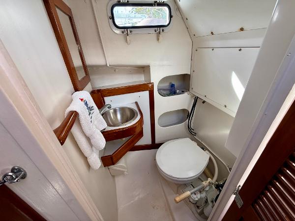 1978 Dyer 29 Trunk Cabin bathroom with sink, toilet, and porthole window.
